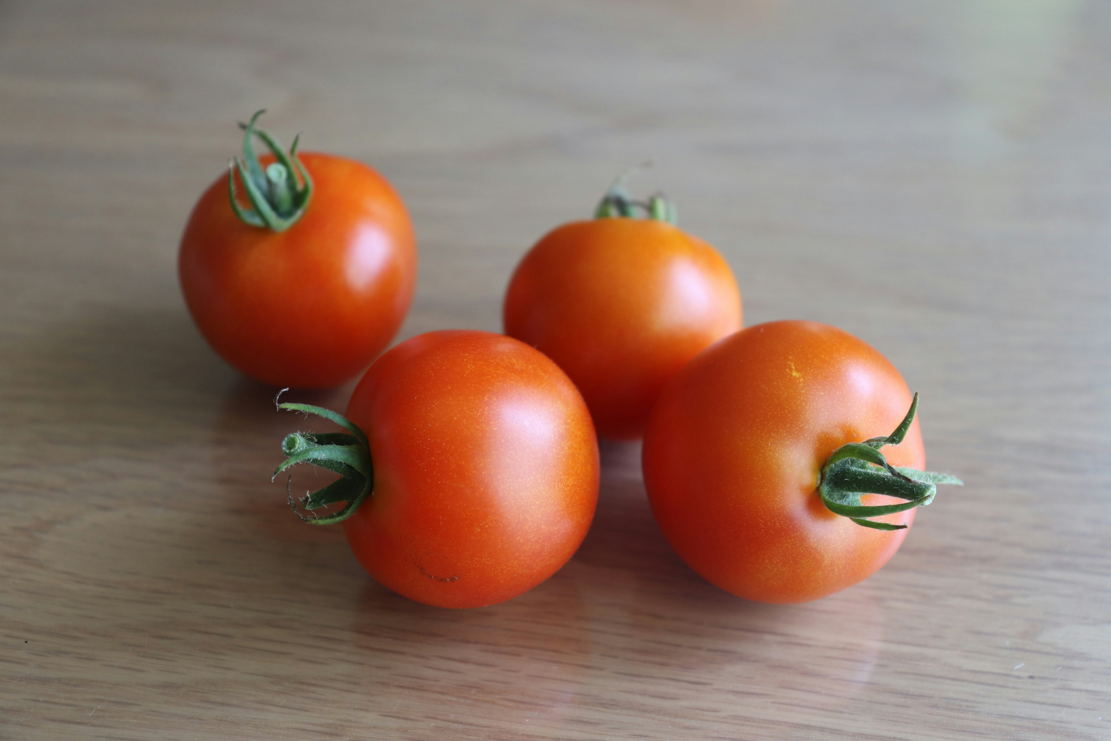 Fresh orange tomatoes arranged on a wooden table