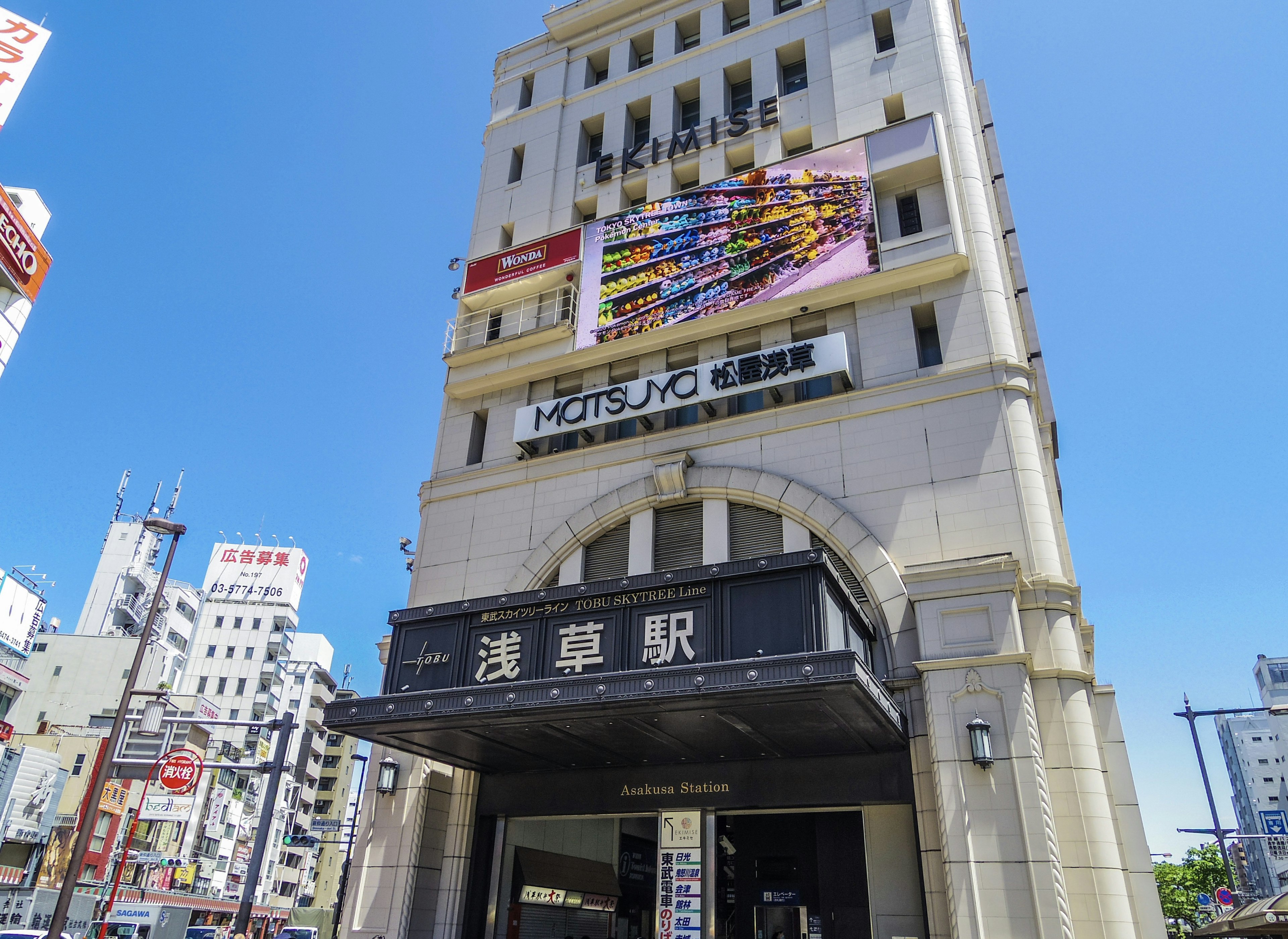 Exterior view of Asakusa Station under a clear blue sky featuring a shopping area