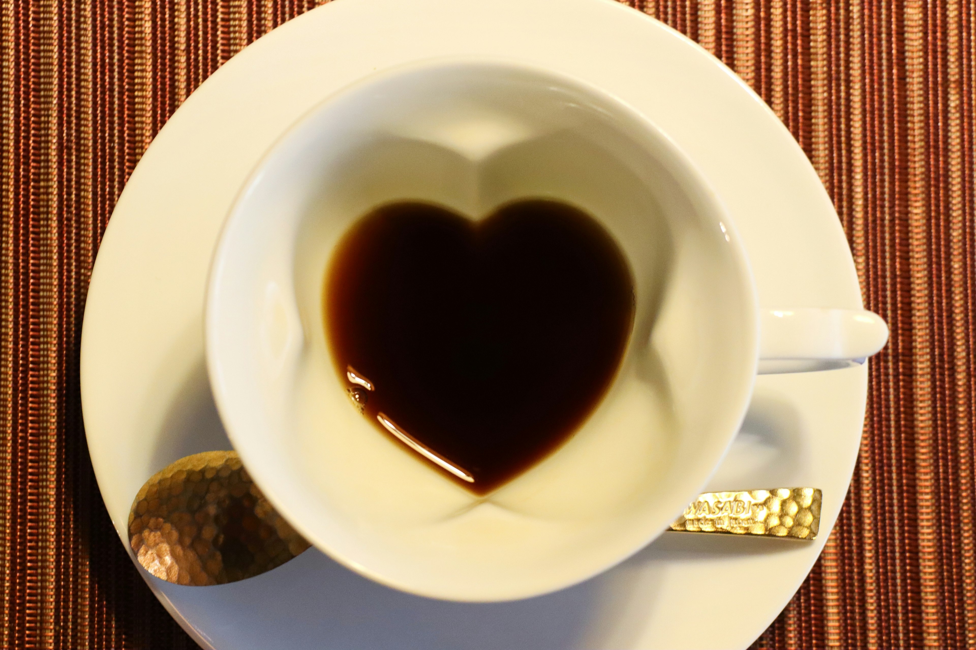 Coffee cup with a heart-shaped pattern in the liquid on a white saucer