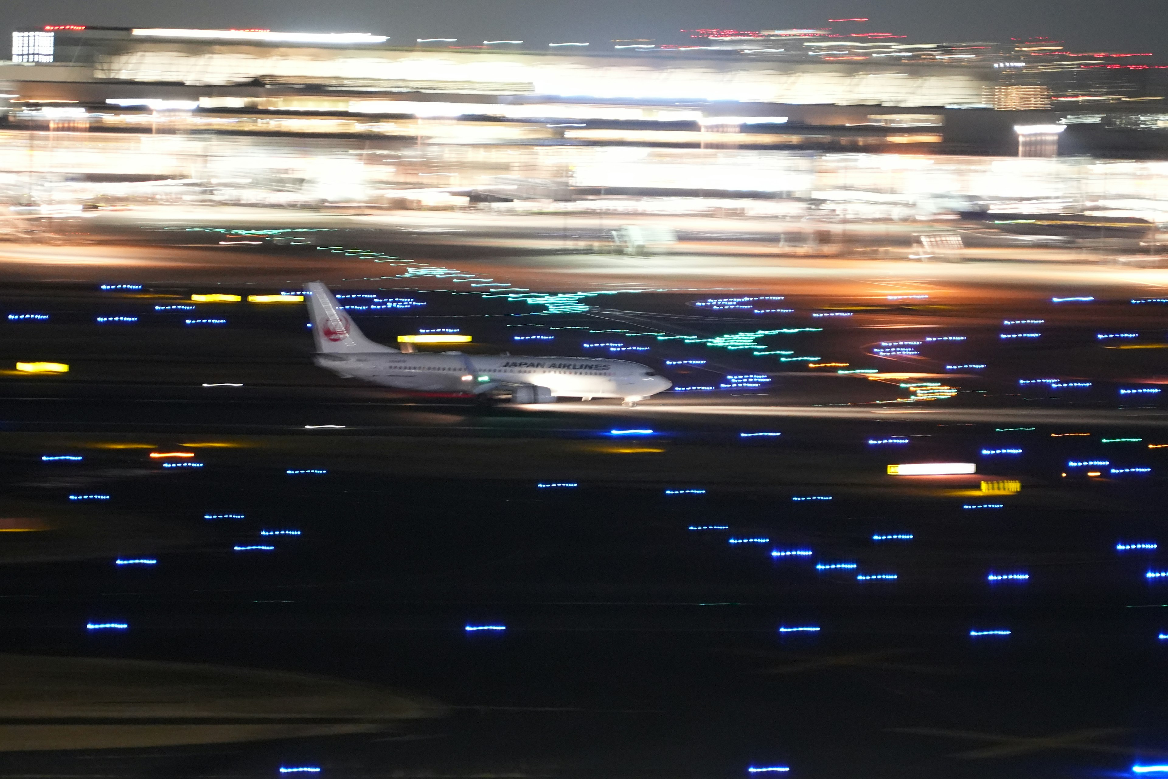 Blurry image of an airplane taking off at night with illuminated runway lights