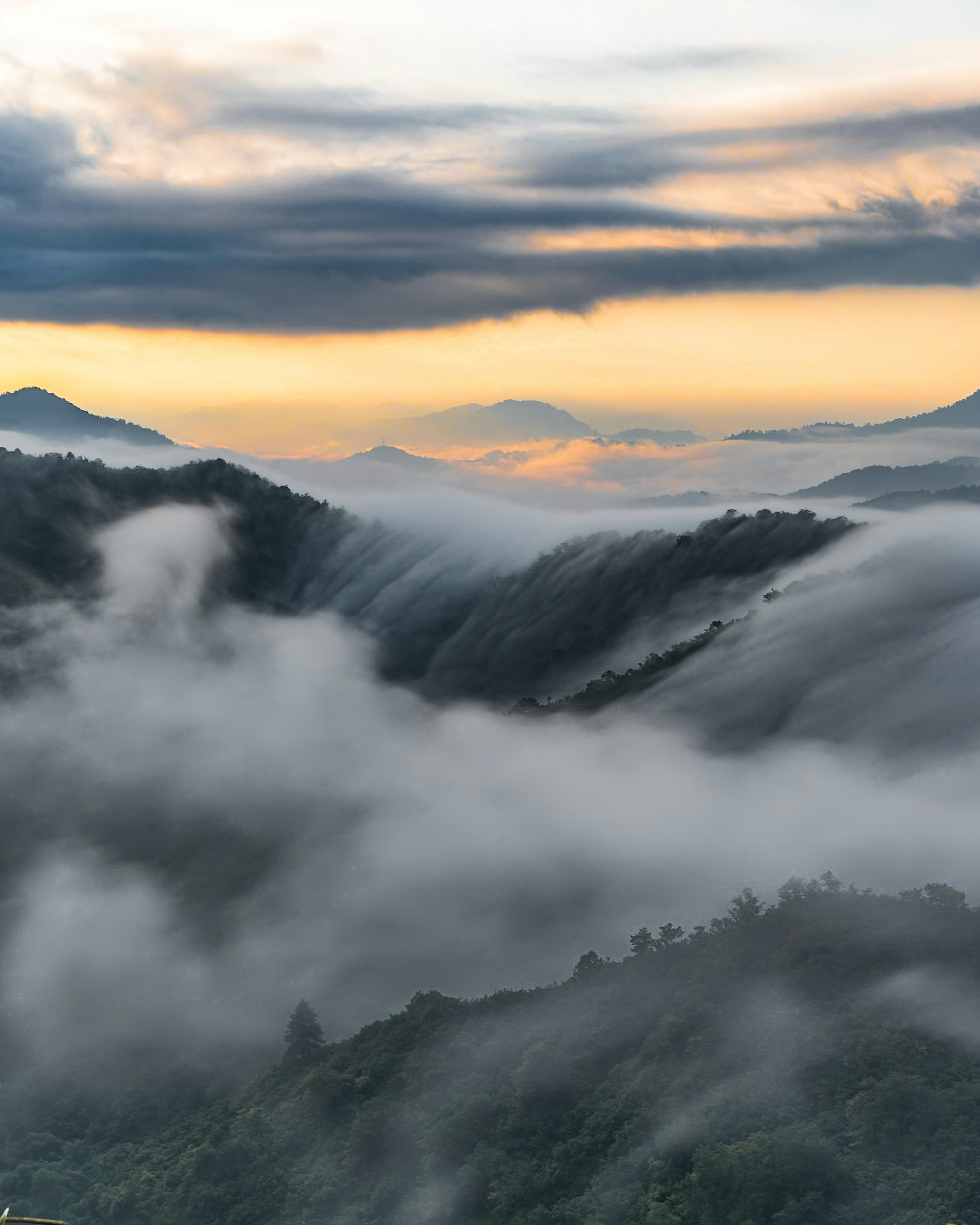 Vue panoramique des montagnes brumeuses à l'aube avec des nuages doux