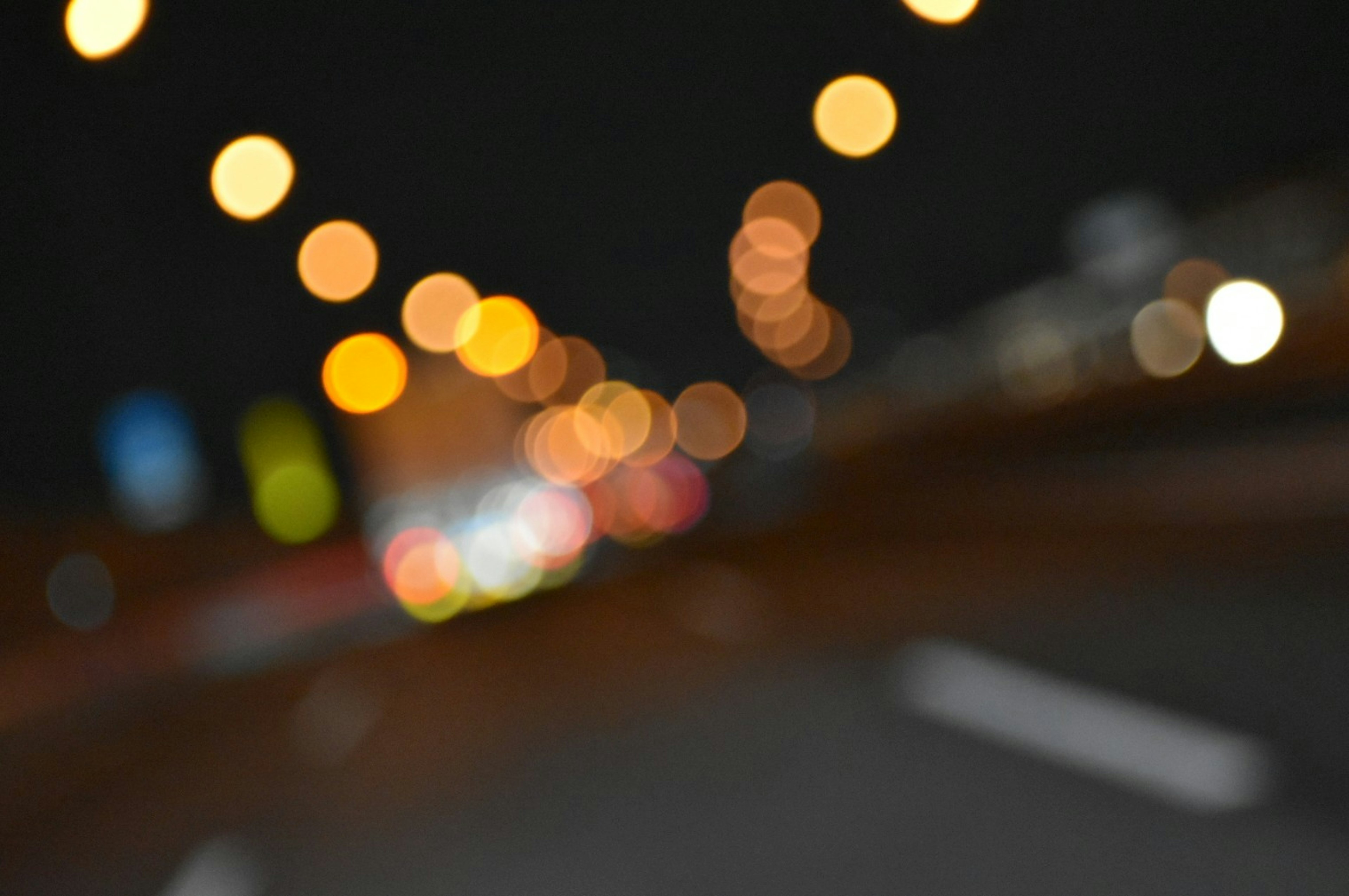 Blurred night road with glowing bokeh lights and moving vehicles