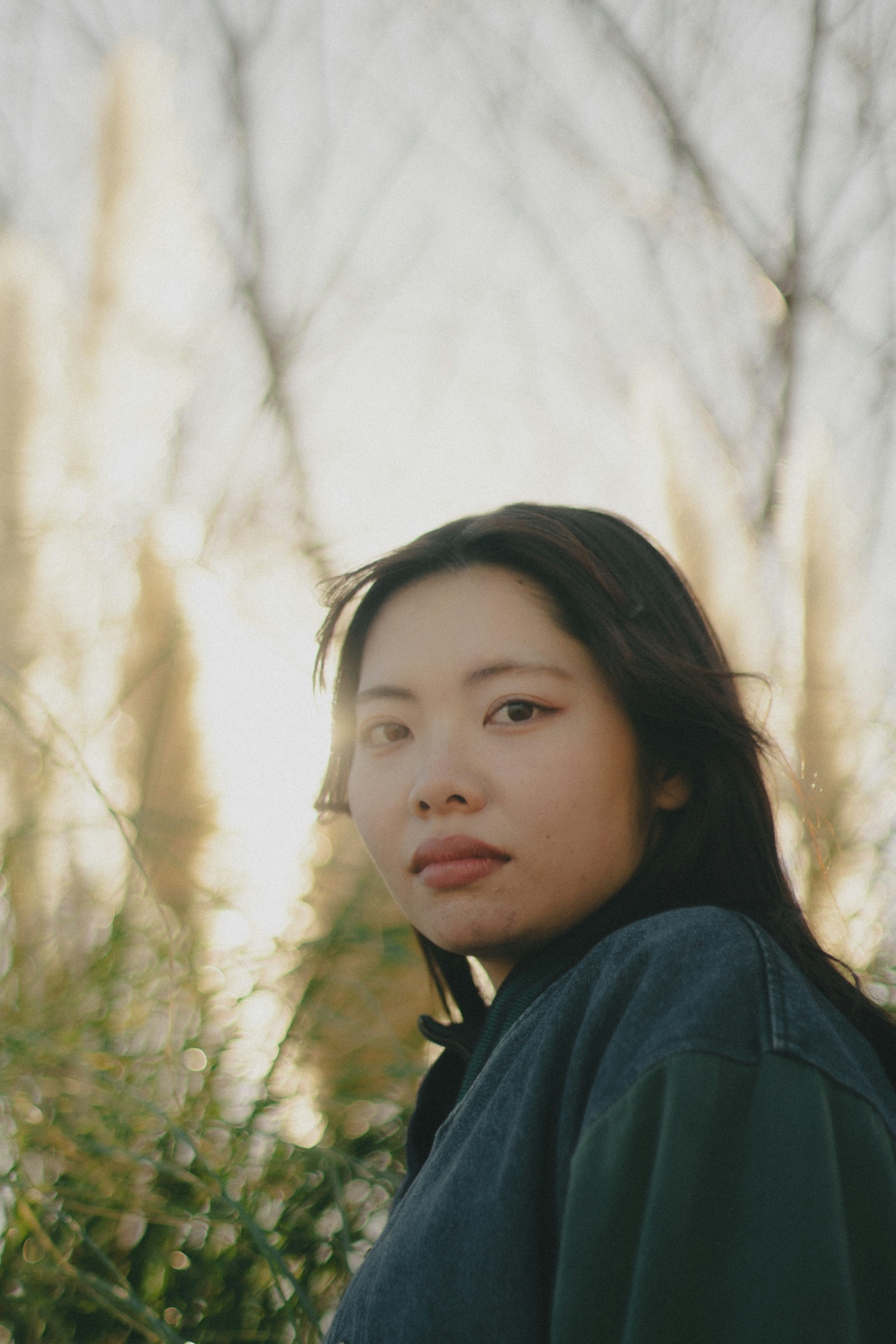 Portrait d'une femme souriante dans la nature avec une lumière douce et de la verdure en arrière-plan