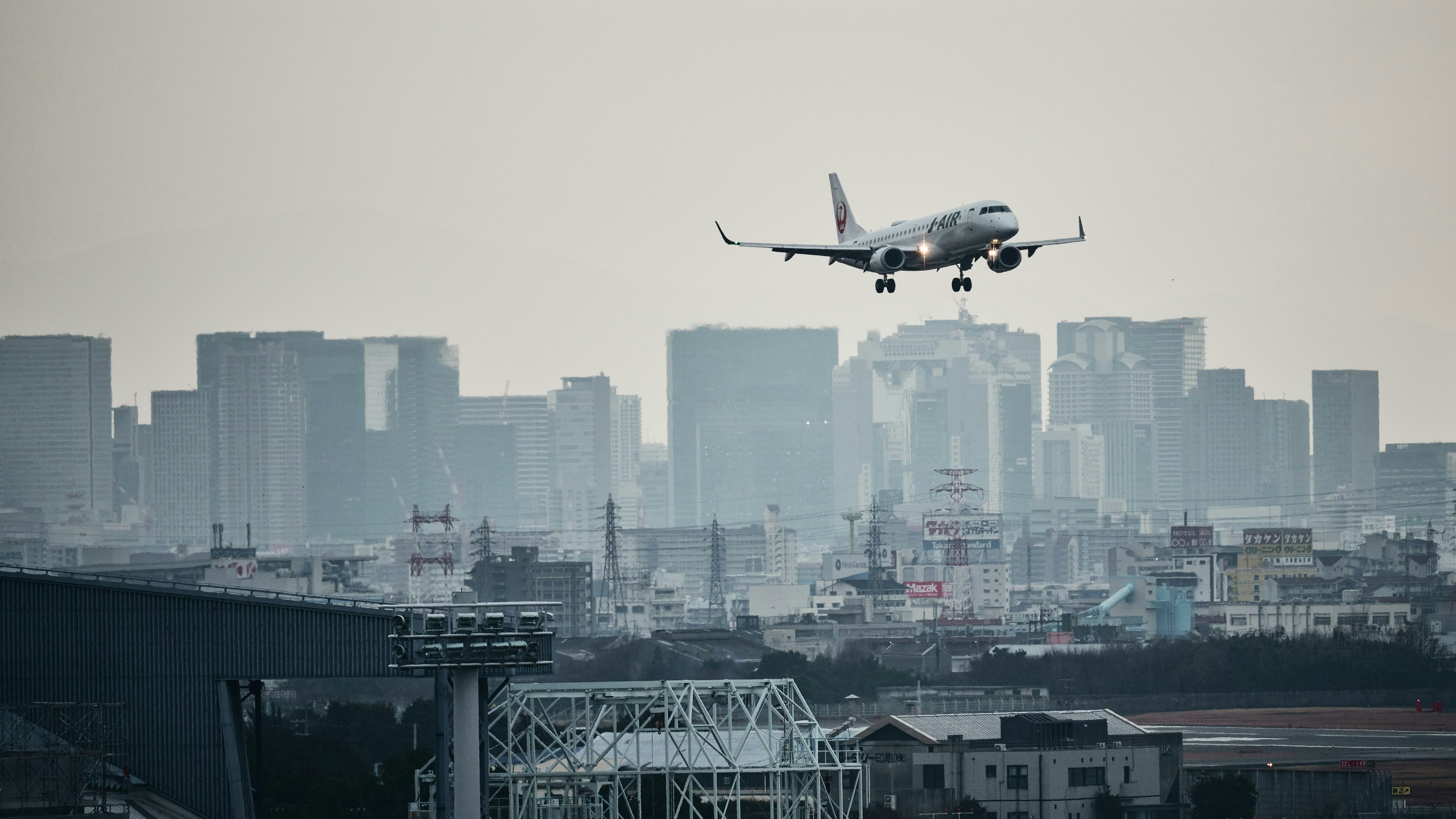 都市の上空を飛ぶ航空機と高層ビルのシルエット