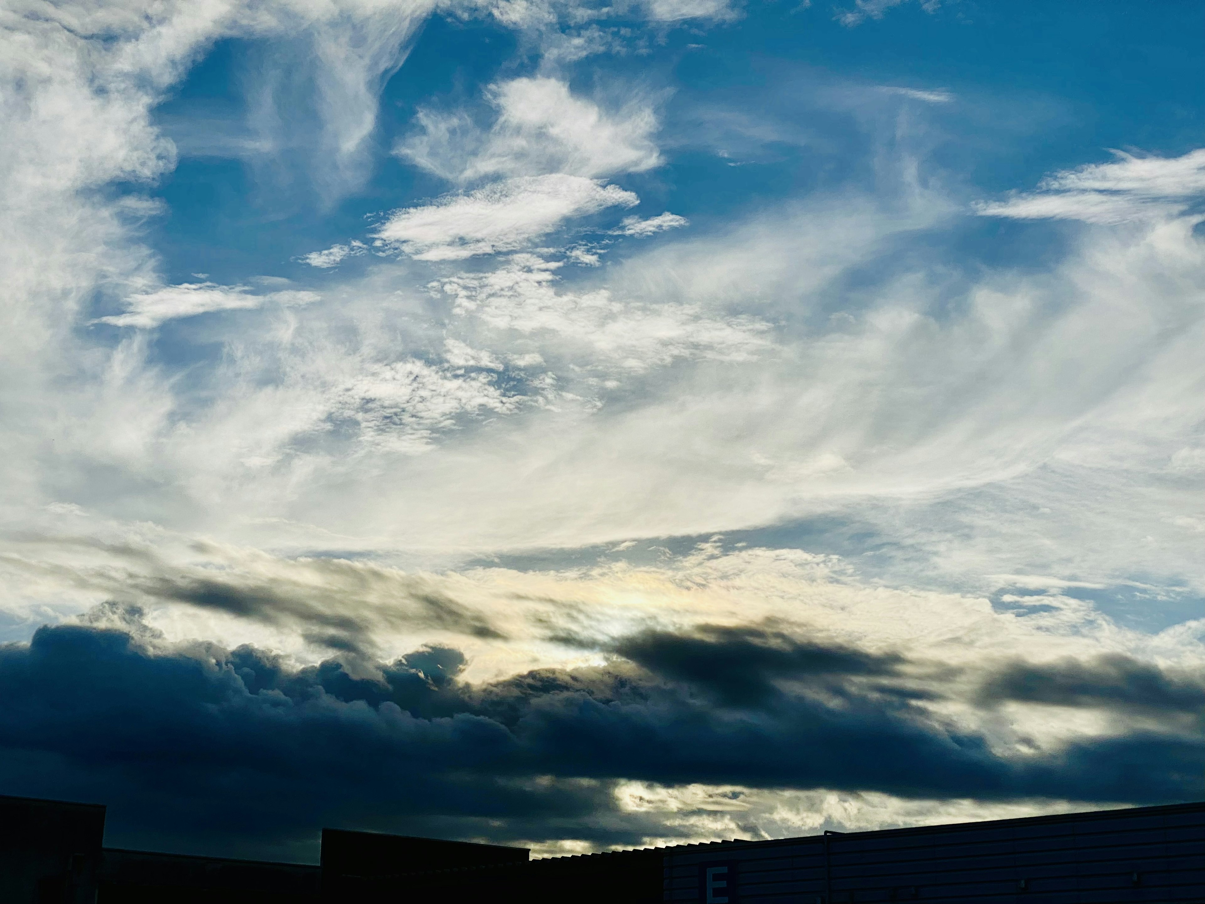 Weitläufiger blauer Himmel mit weißen Wolken und dunklen Wolken in der Ferne