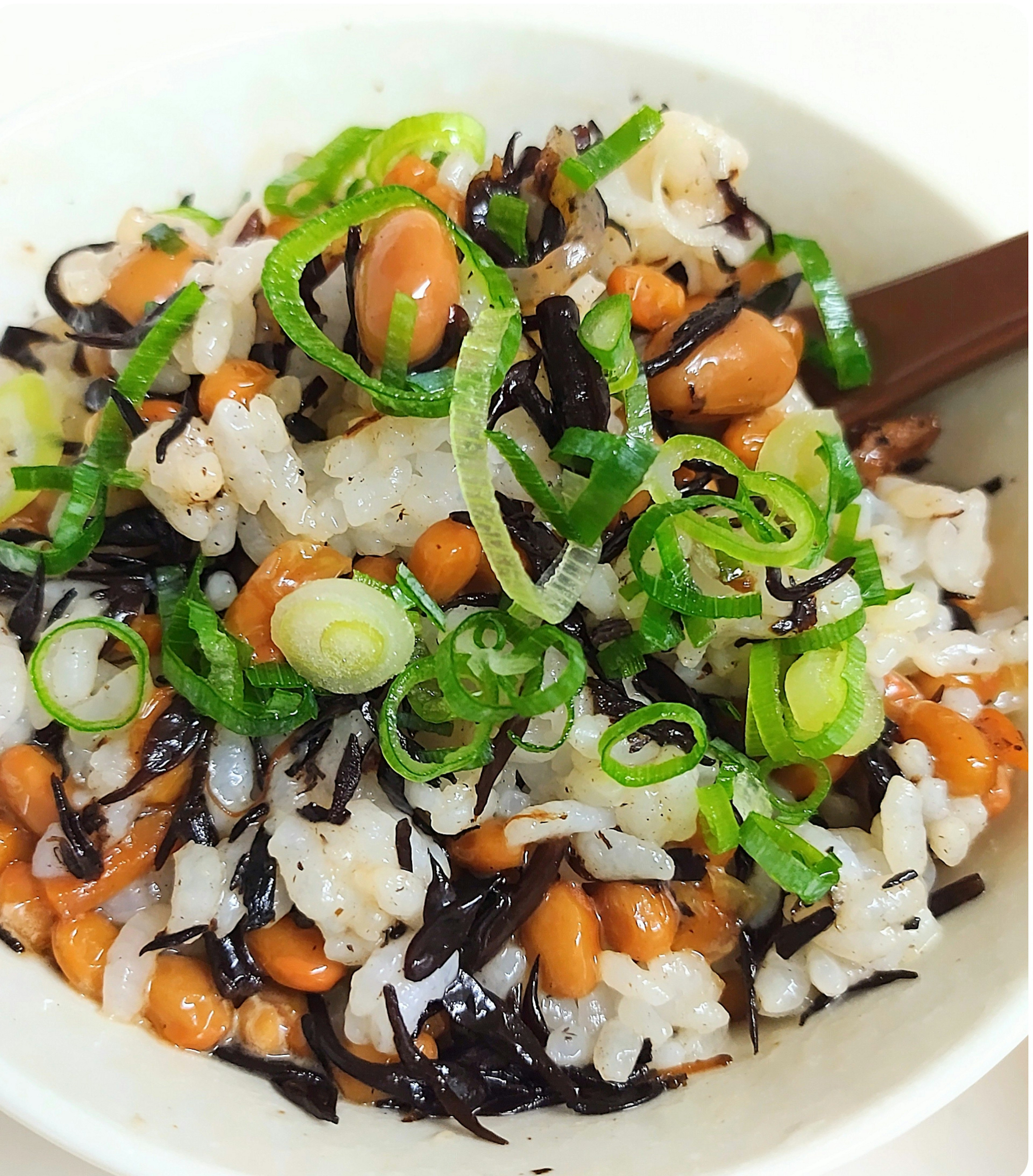 Bowl of rice topped with hijiki seaweed, beans, and green onions