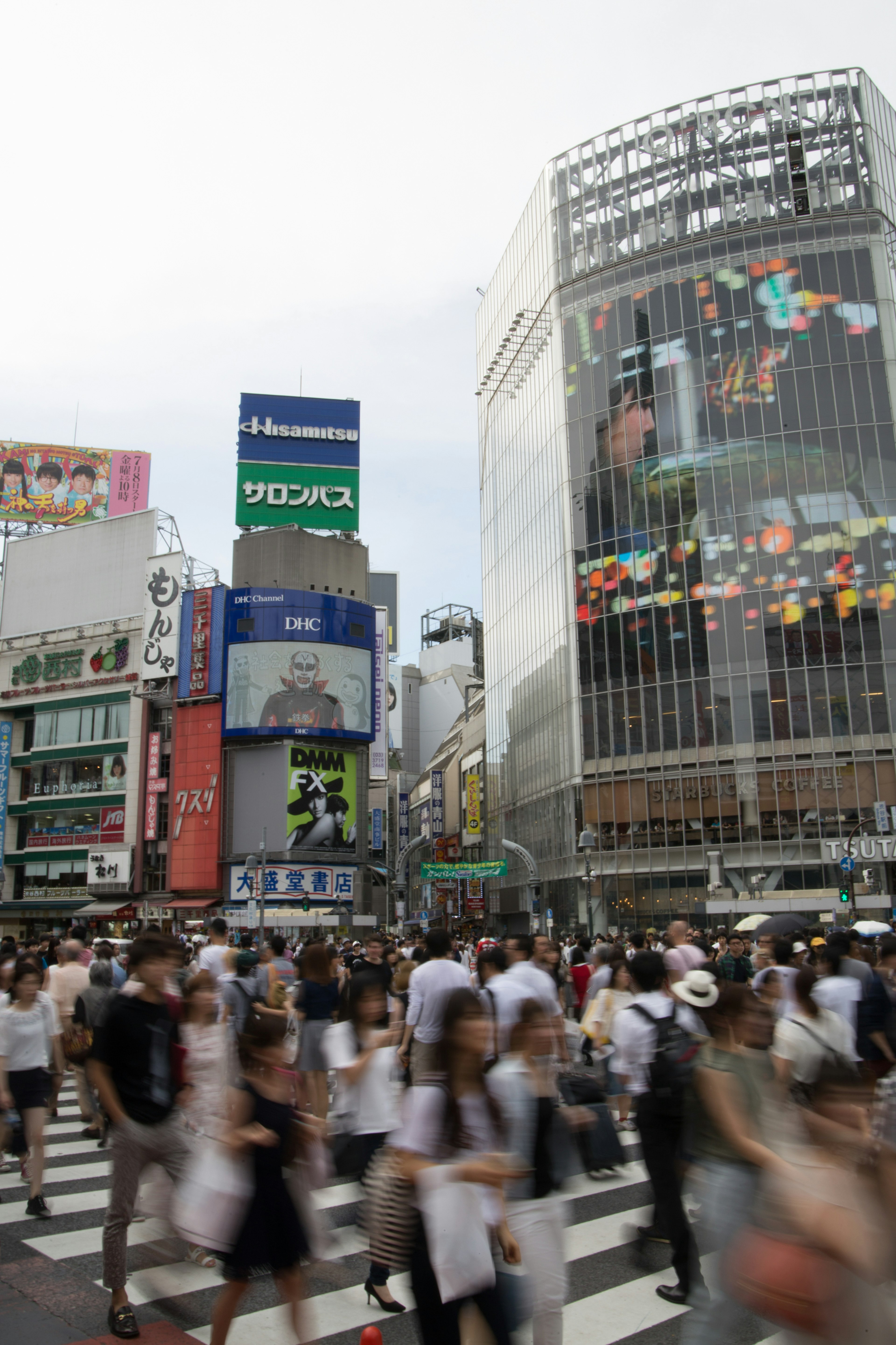 Cruce concurrido de Shibuya con peatones y anuncios en los edificios