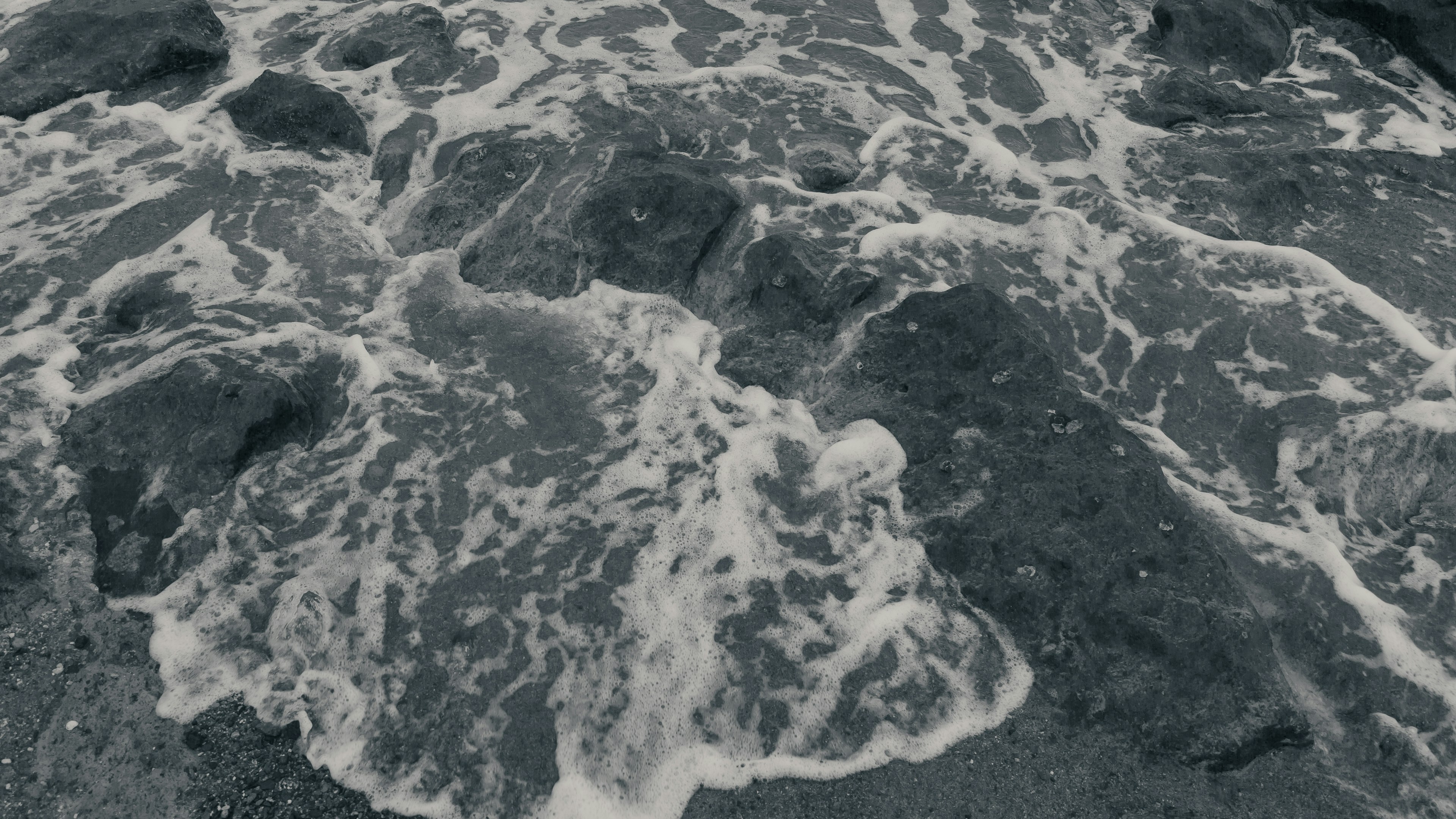 Black and white waves crashing against rocks in the sea