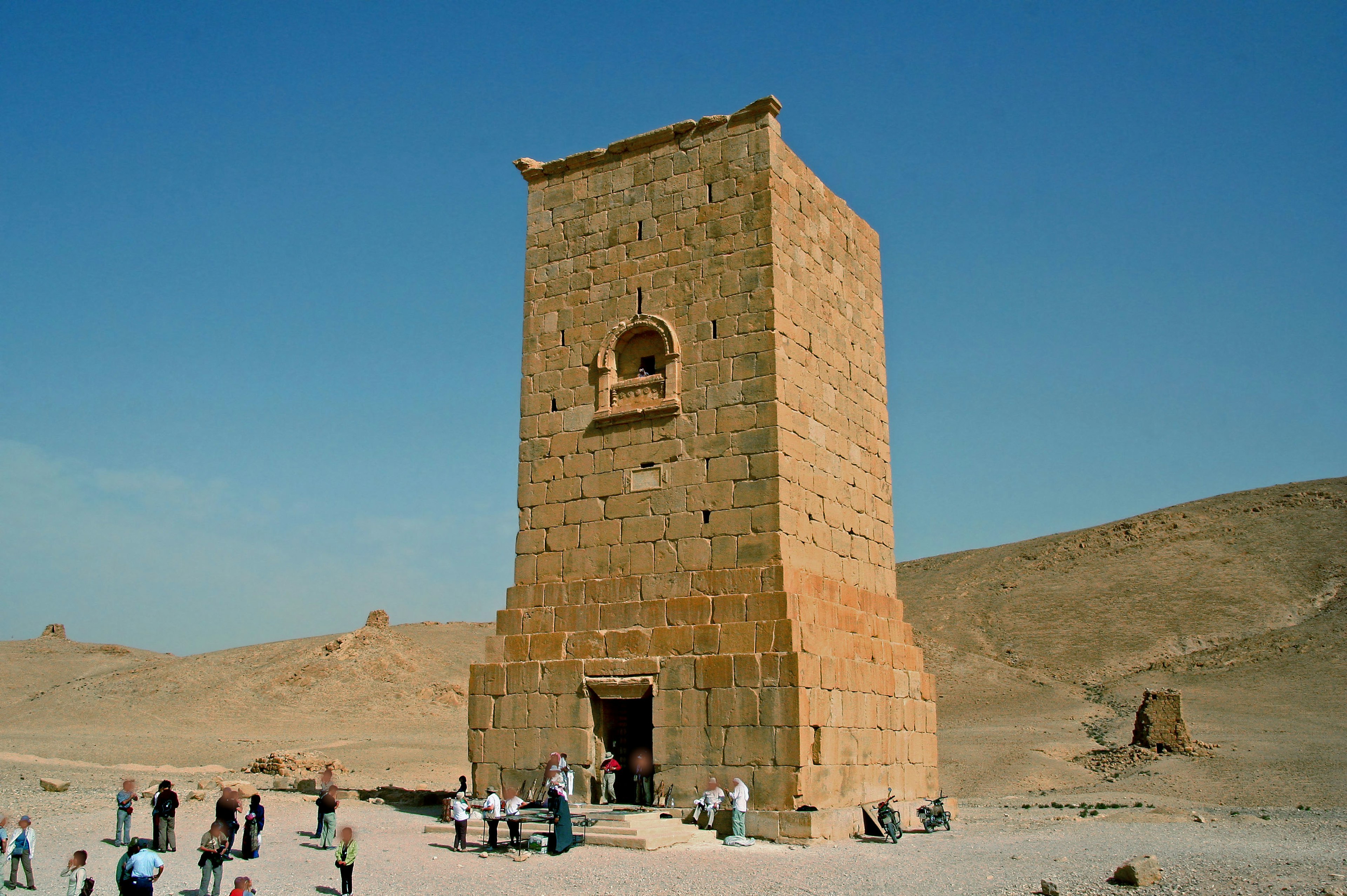 Torre antigua con turistas en un paisaje desértico