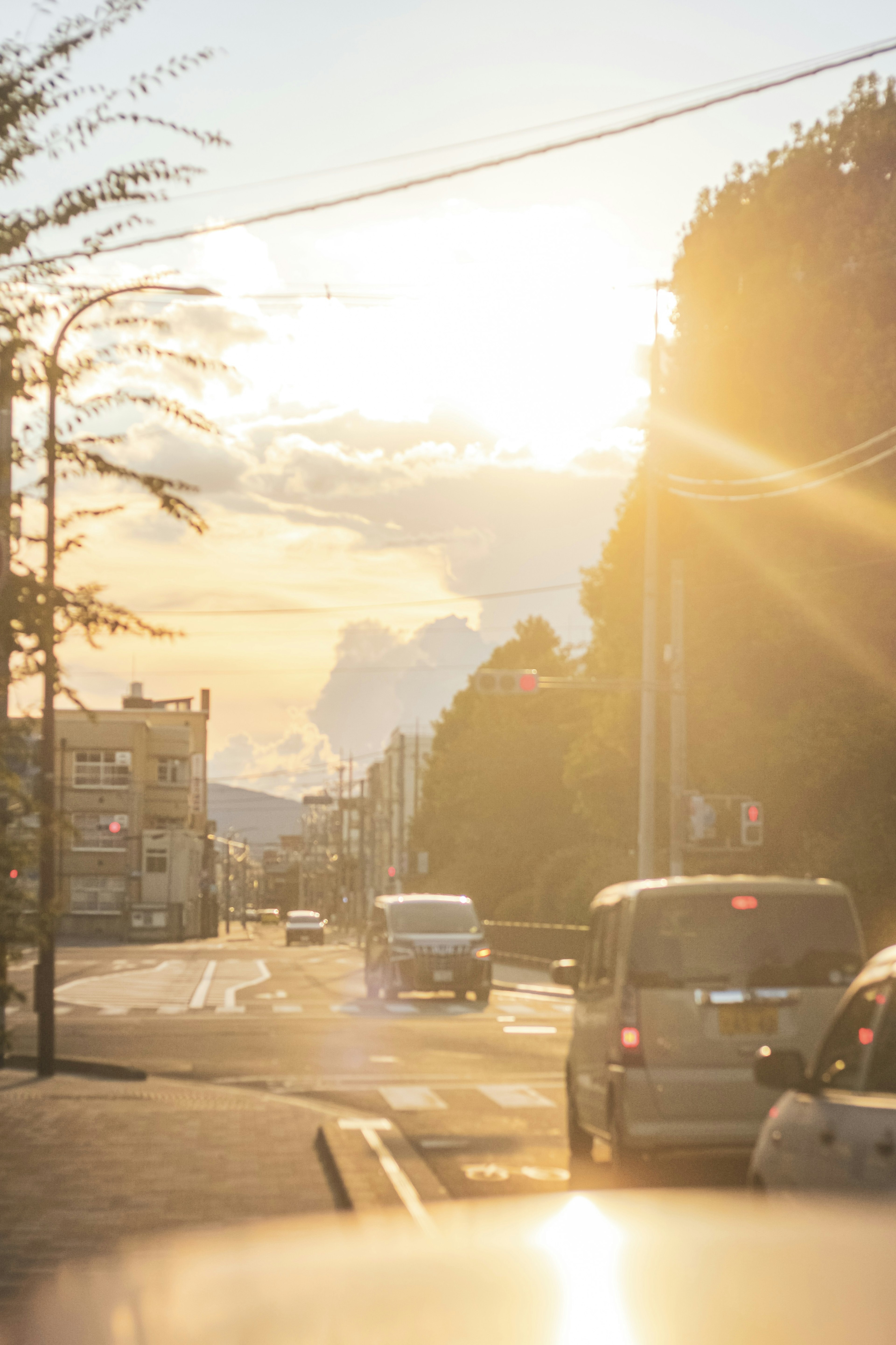 Straßenszene mit Sonnenlicht, das durch die Wolken scheint Autos auf der Straße