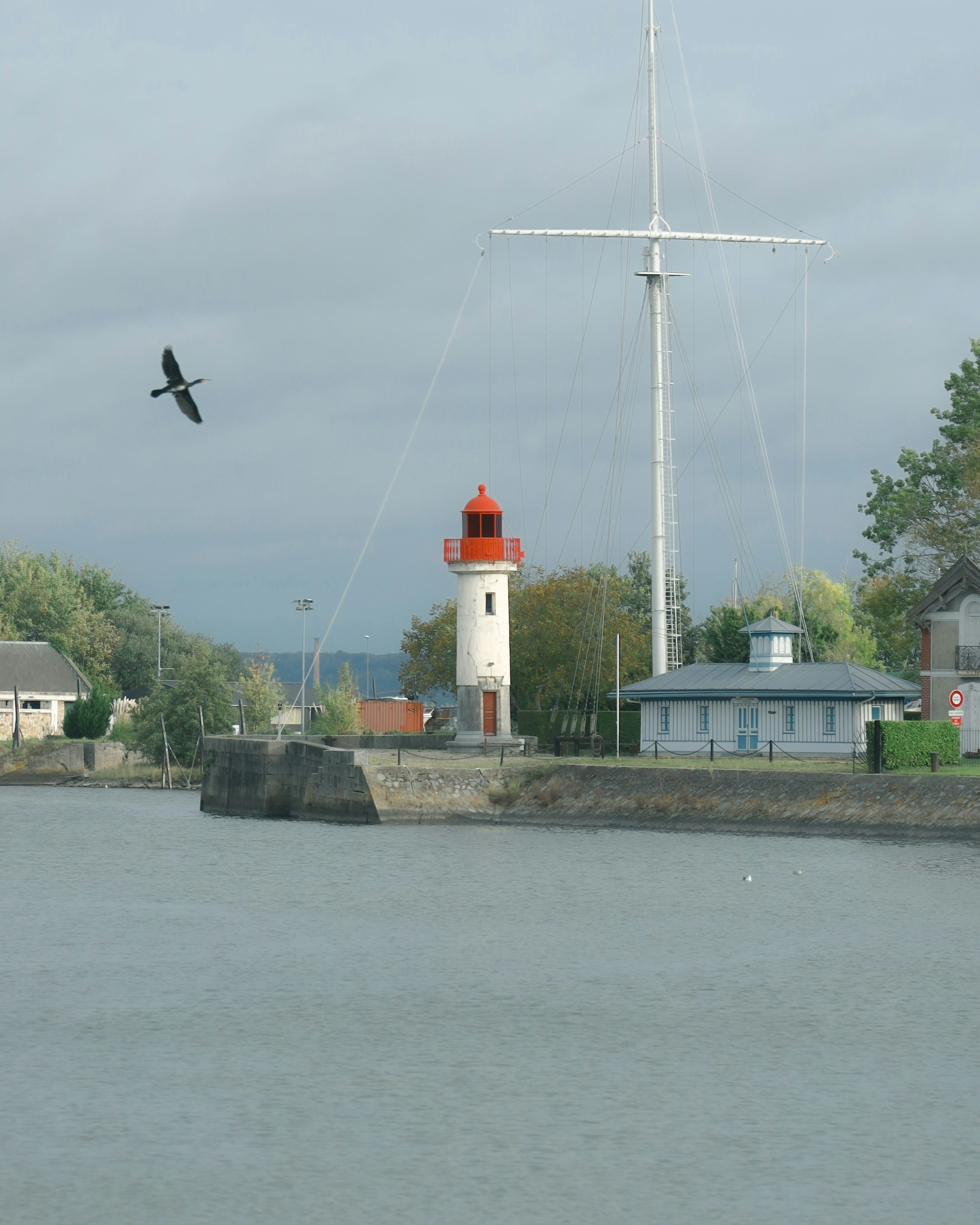 Leuchtturm mit rotem Dach am Hafen umgeben von Grünflächen