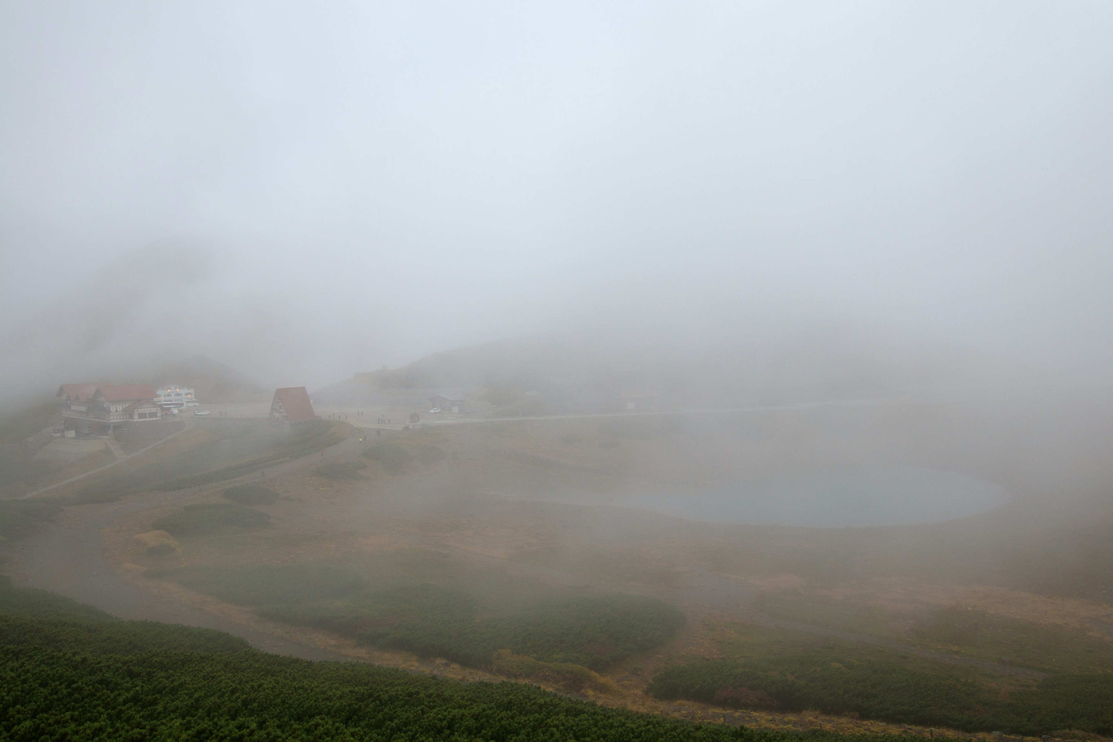 Foggy landscape featuring scattered houses and a lake