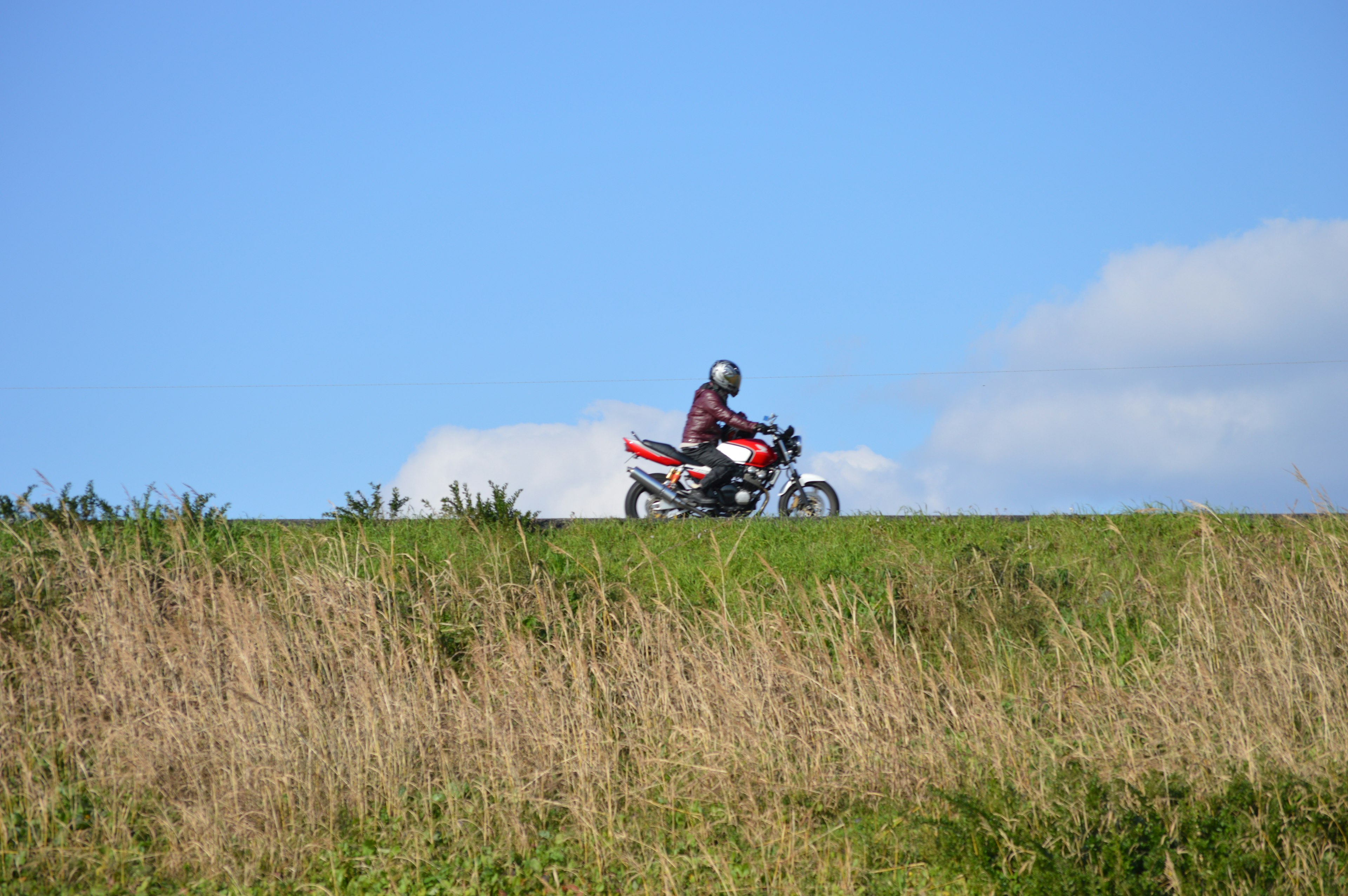 Rider su una moto contro un cielo blu e un paesaggio erboso