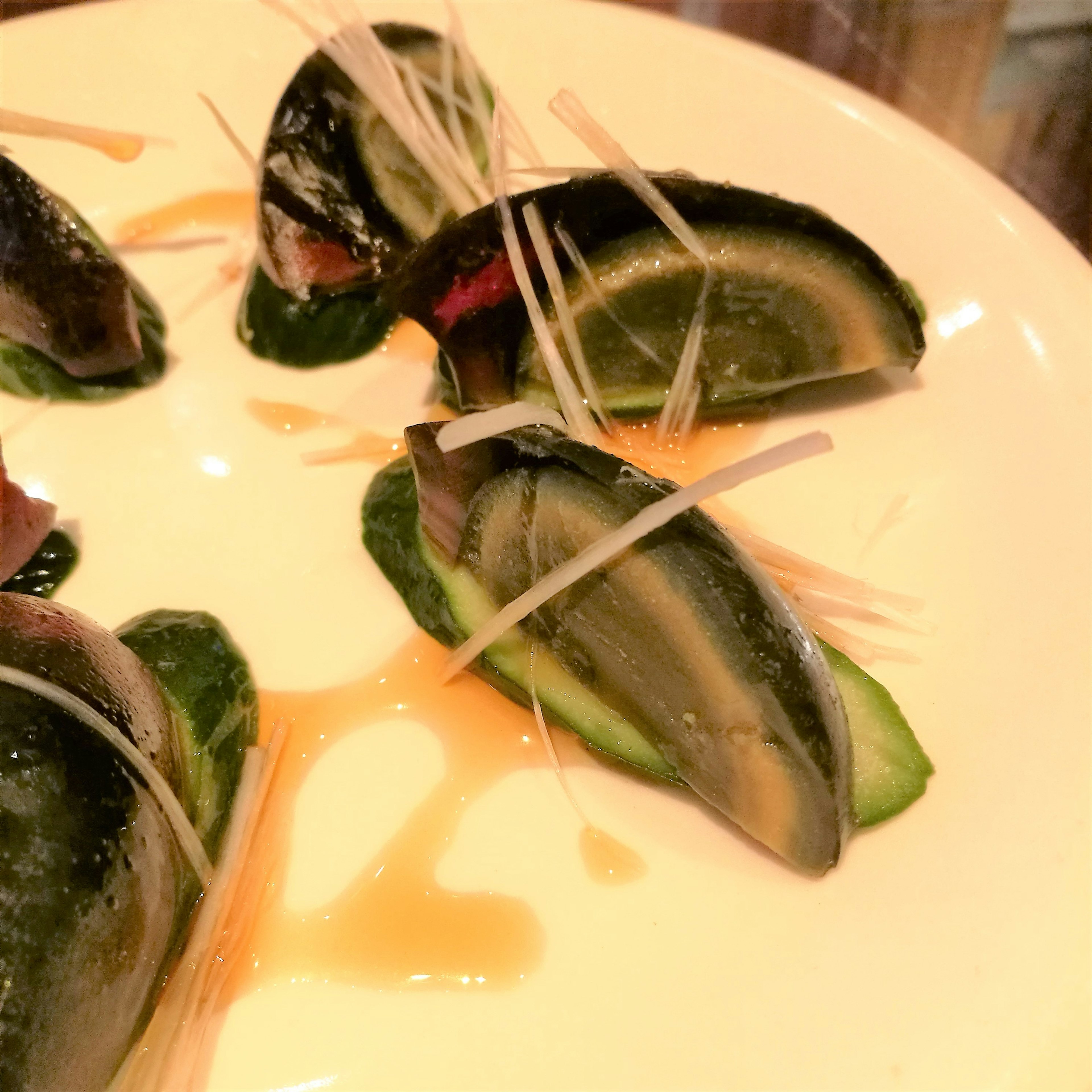 Sliced century eggs served on a plate with cucumber and garnished with ginger