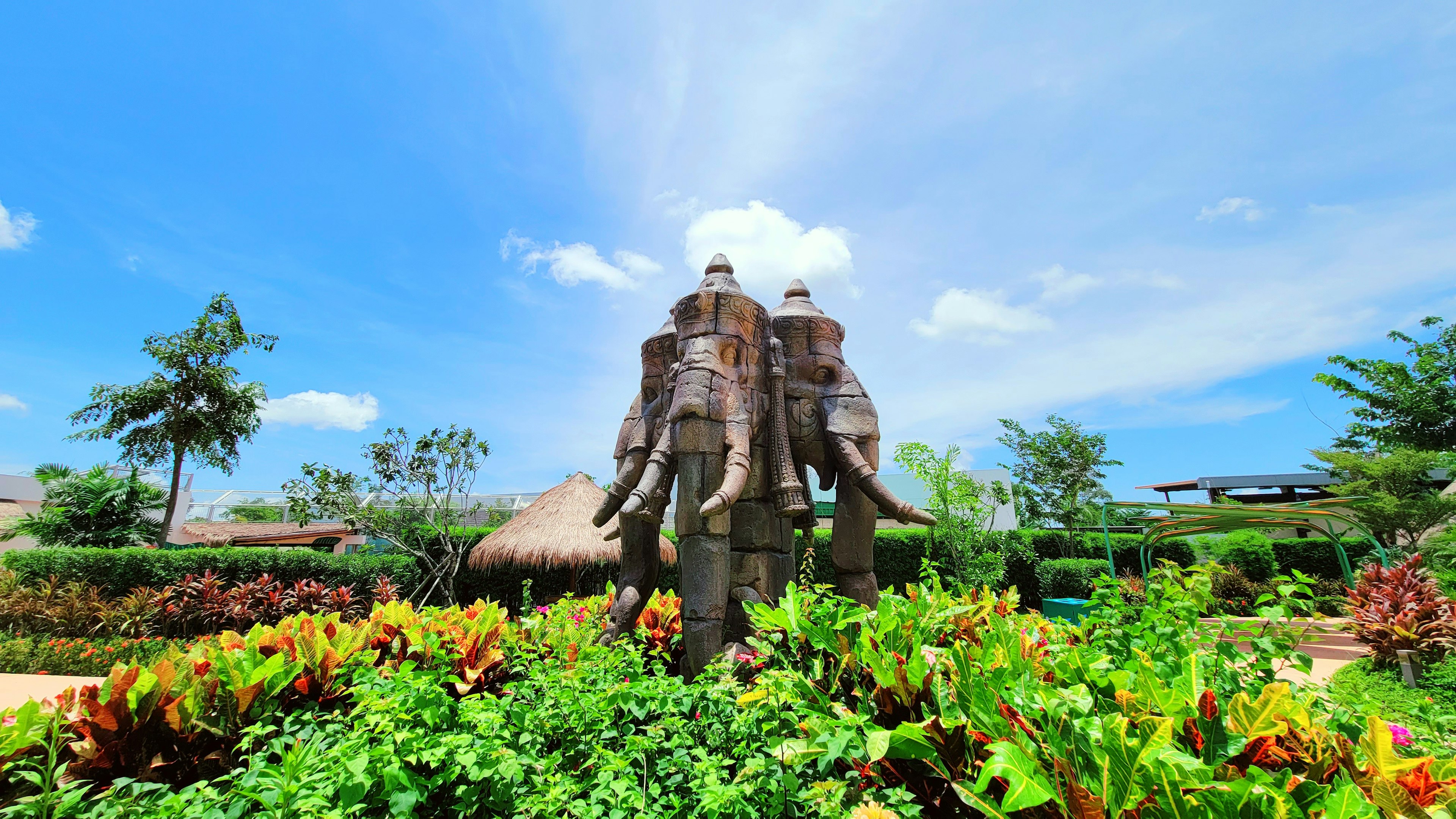 Sculpture d'éléphants sous un ciel bleu entouré de verdure luxuriante