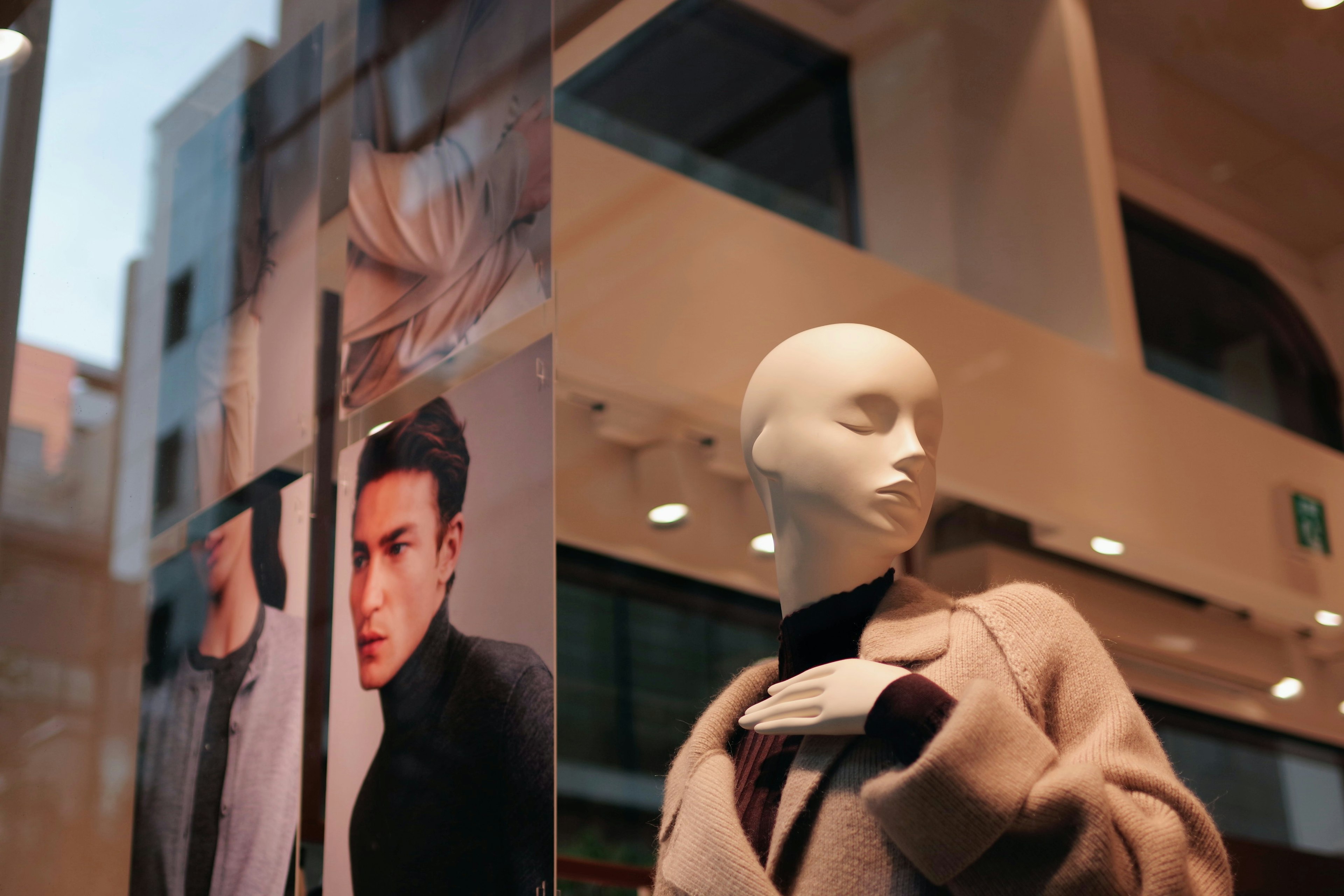 Mannequin in a storefront with fashion posters in the background