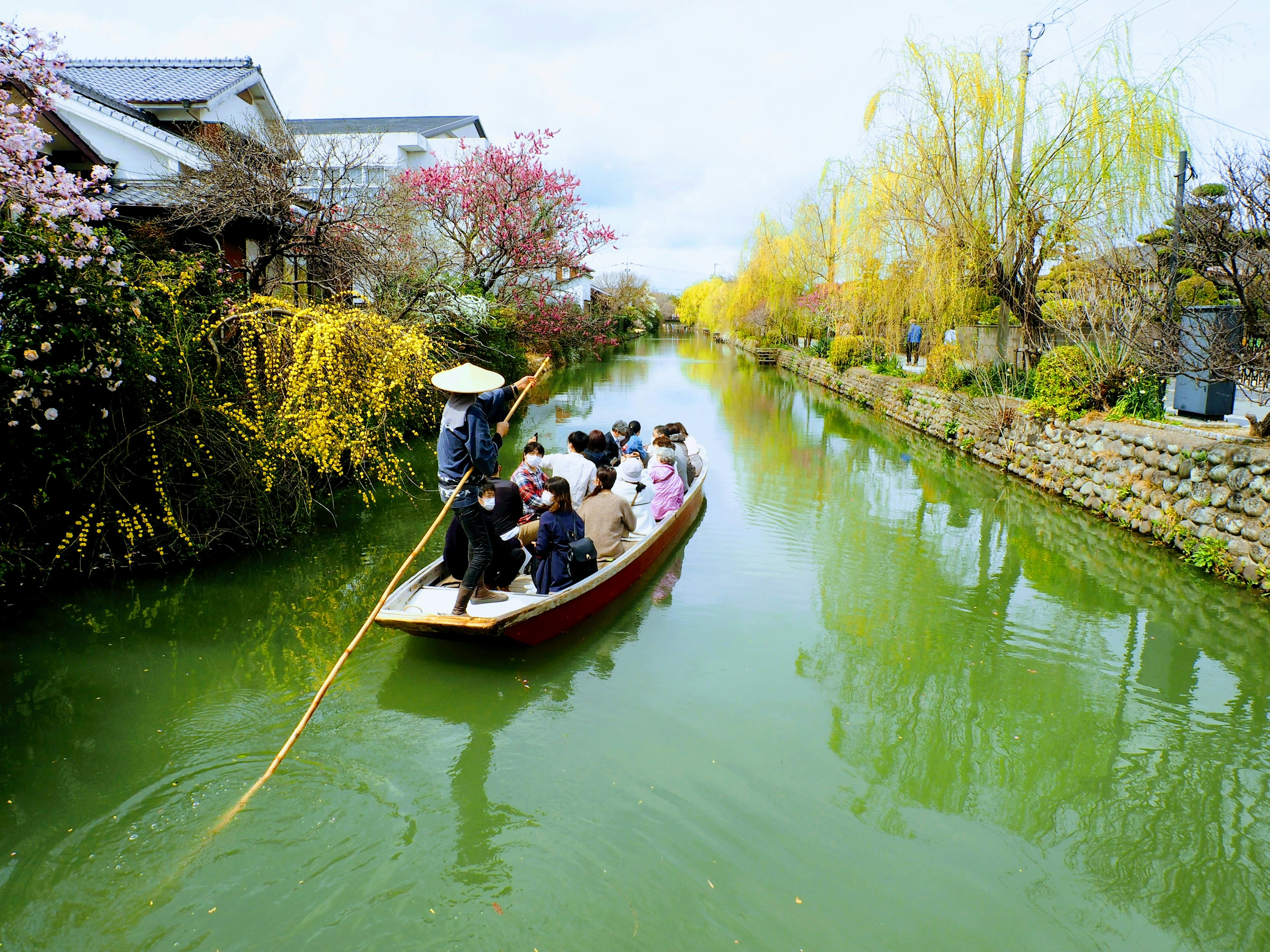 Persone su una barca in un canale colorato circondato da fiori in fiore