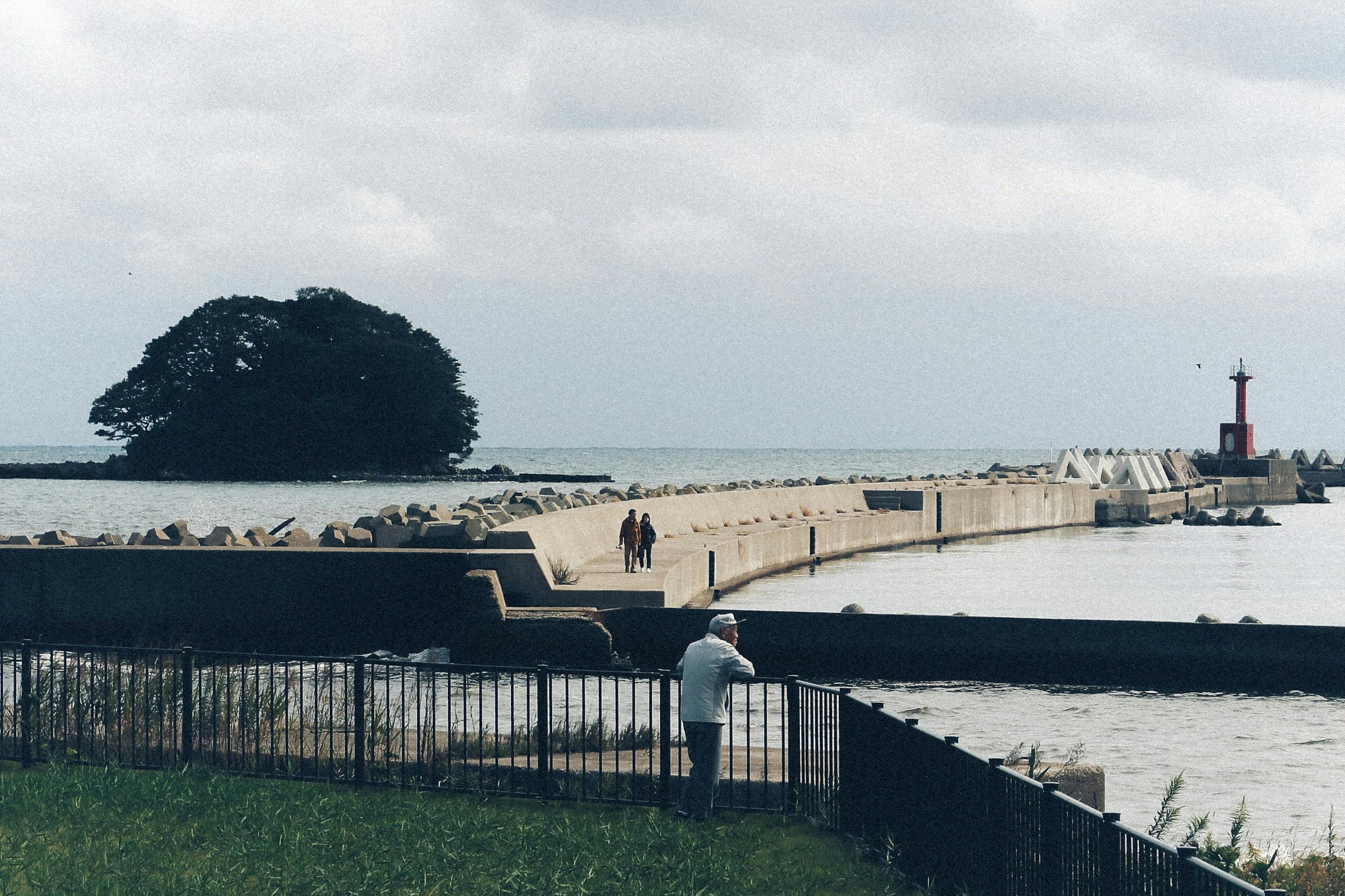 Pemandangan tepi laut dengan breakwater dan mercusuar di latar belakang