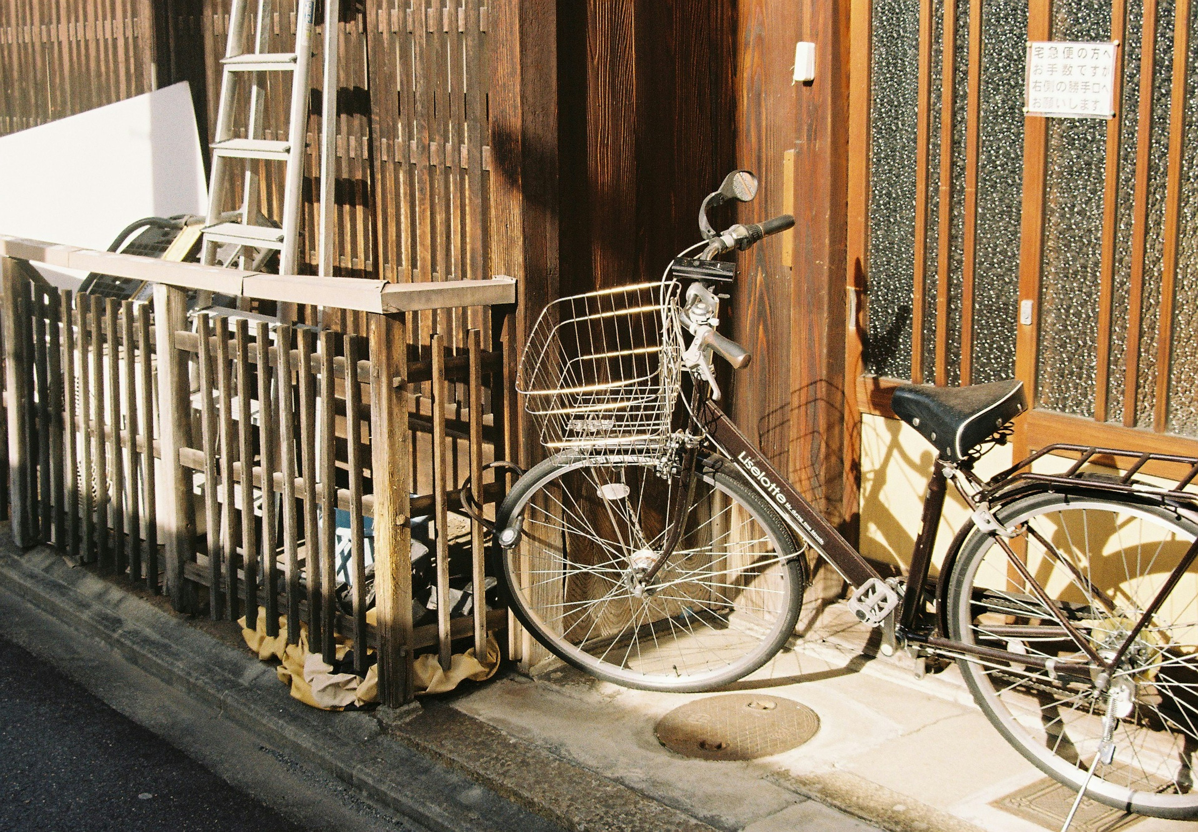 Una bicicletta parcheggiata accanto a una recinzione di legno in una strada giapponese