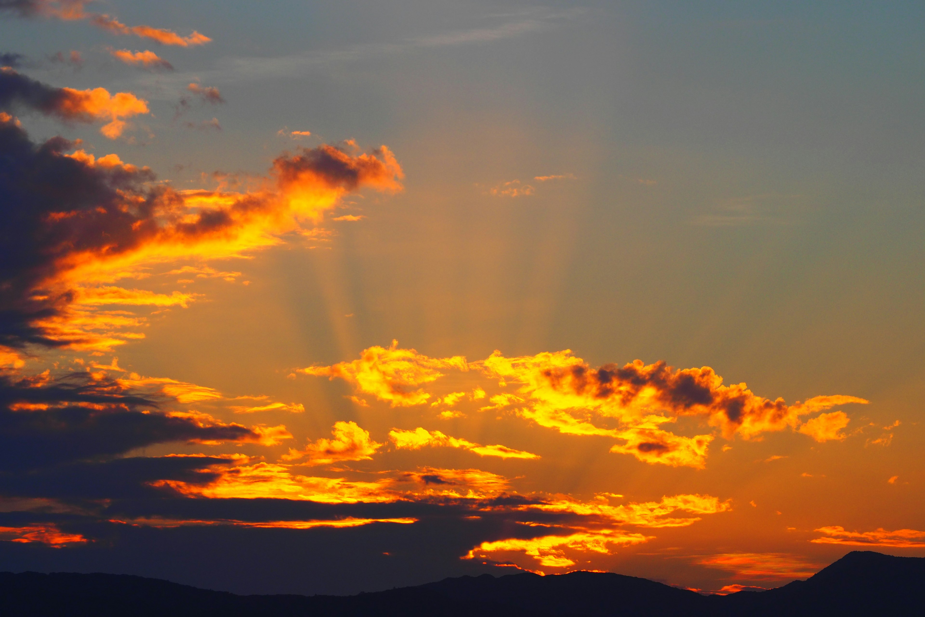 Impresionante atardecer con nubes naranjas y moradas iluminadas por rayos de luz