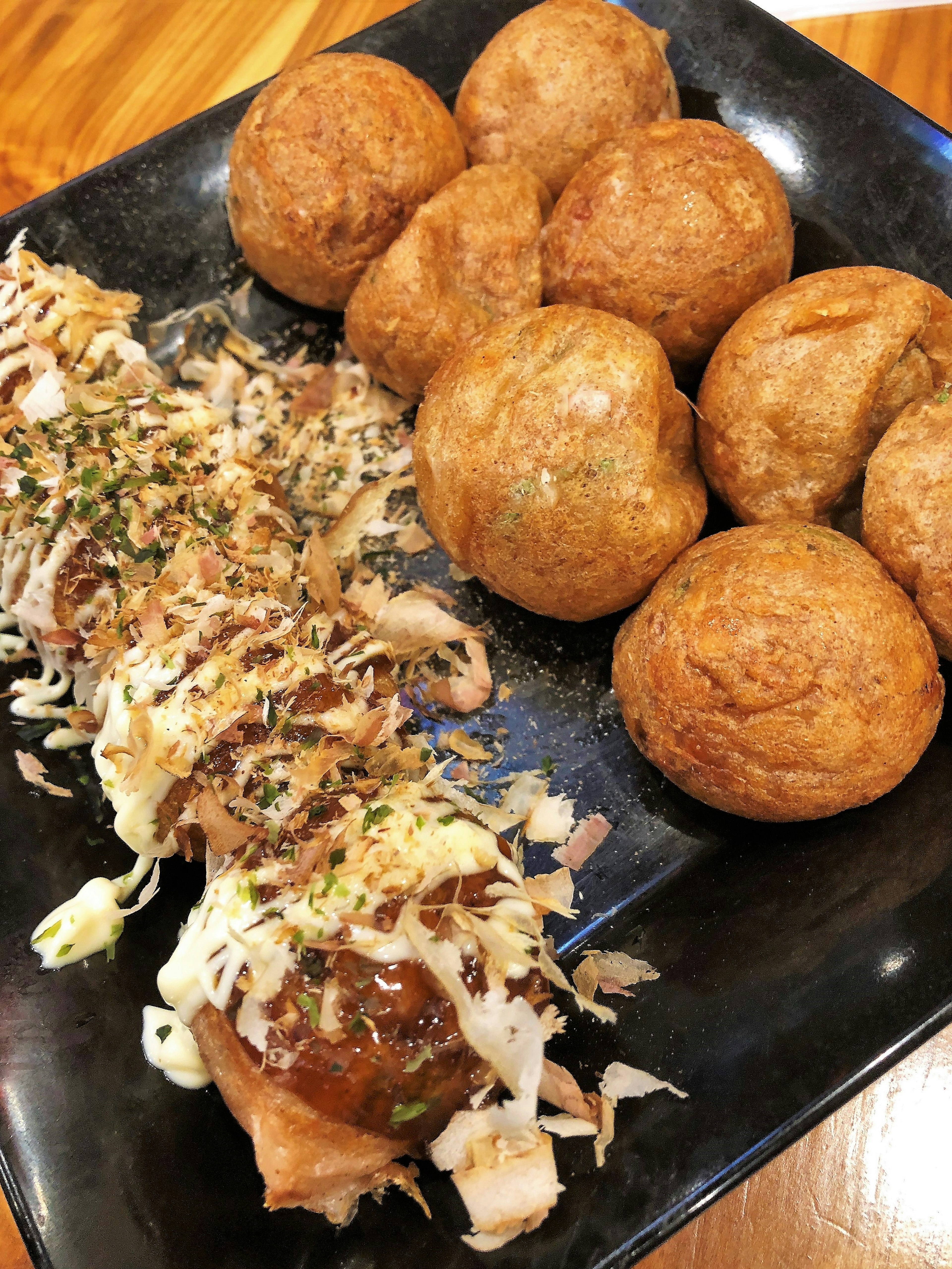 Đĩa takoyaki và bánh bao chiên trên đĩa đen