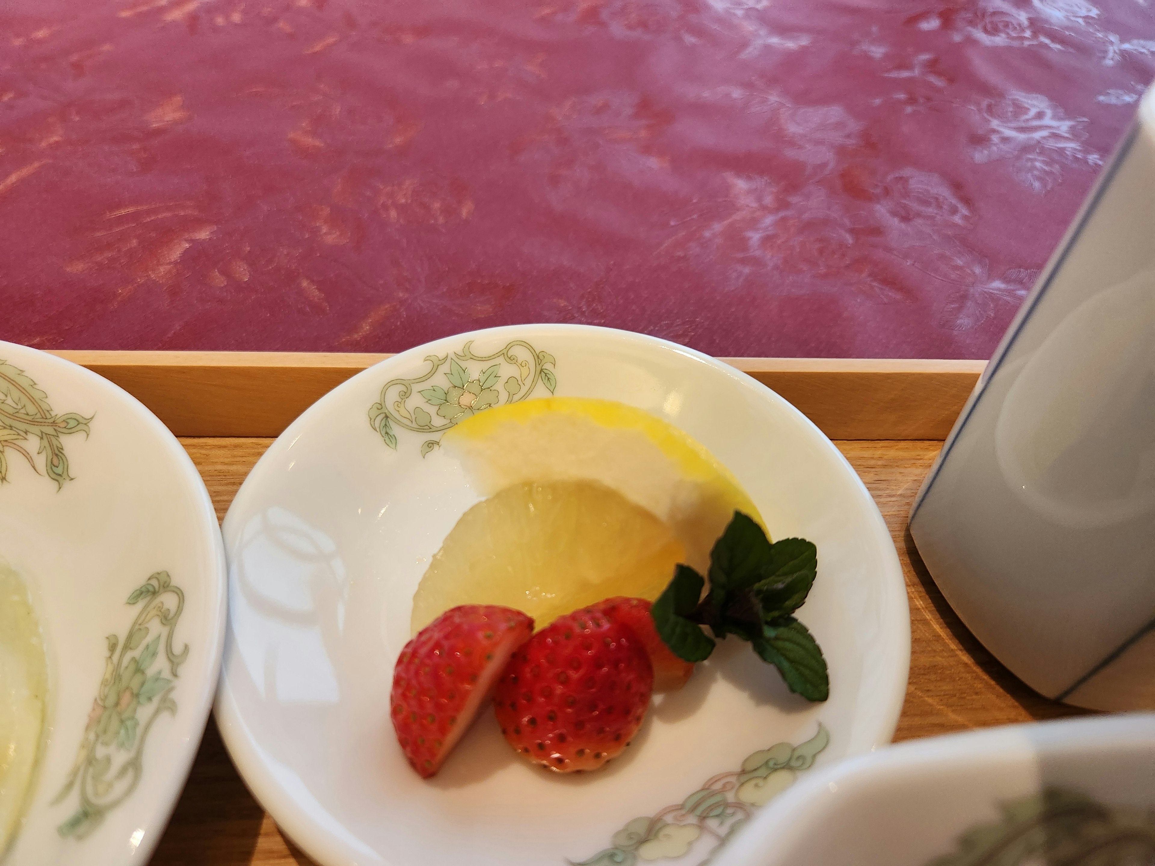 Piatto di dessert con fragole fette di limone e foglie di menta