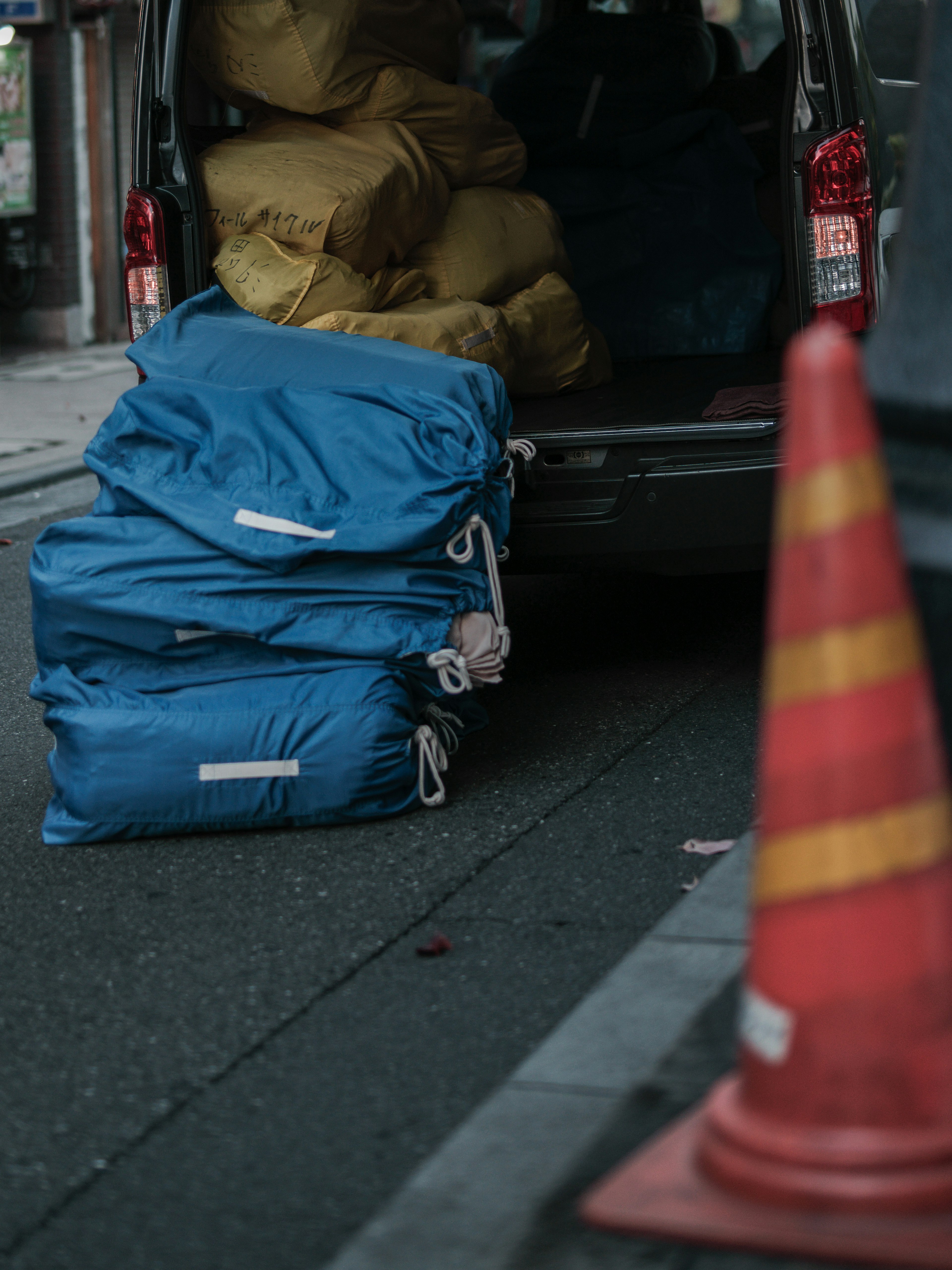 A stack of blue bags next to a van with yellow bags in the back