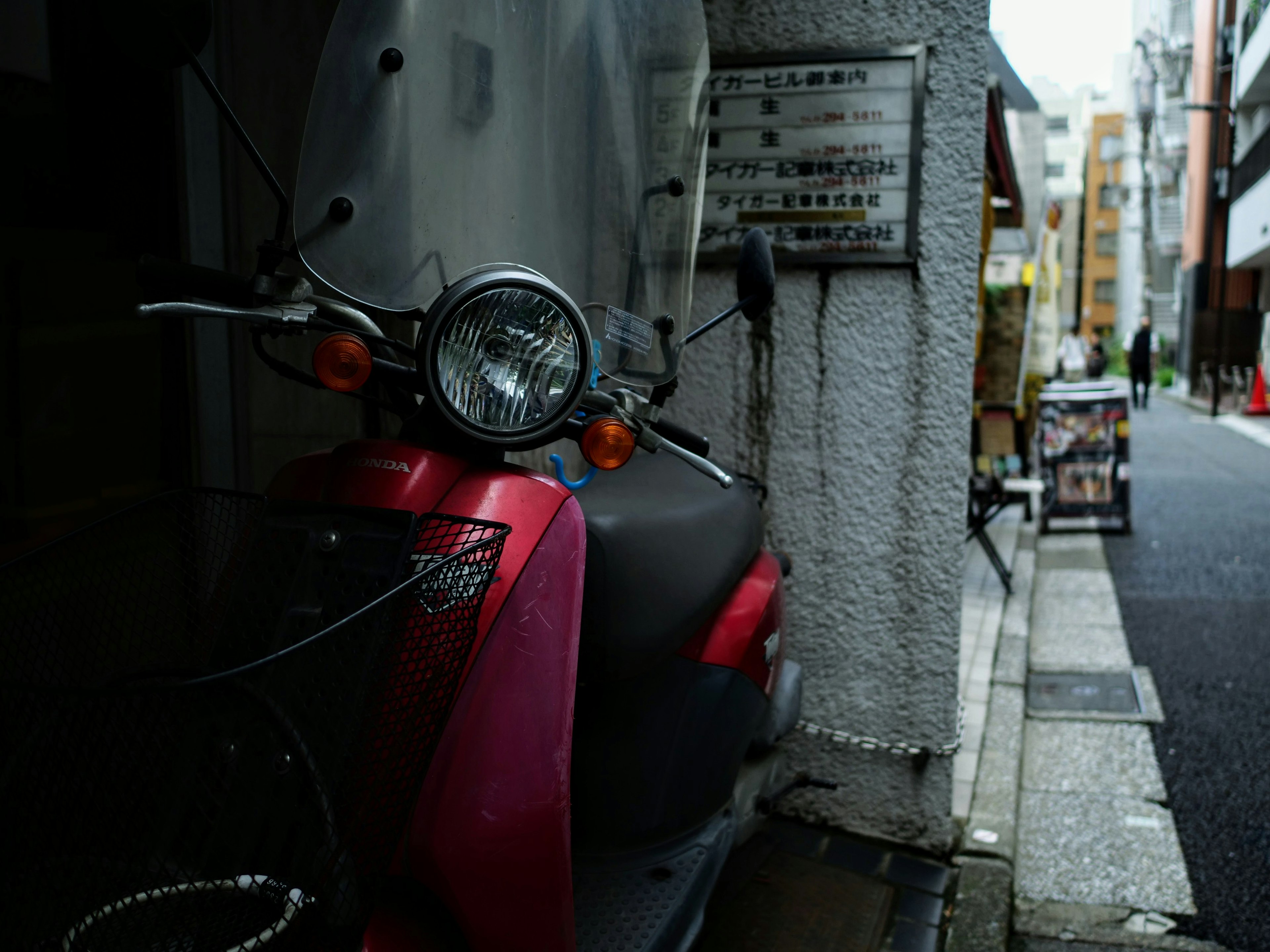 赤いスクーターが狭い路地に停まっている街の風景