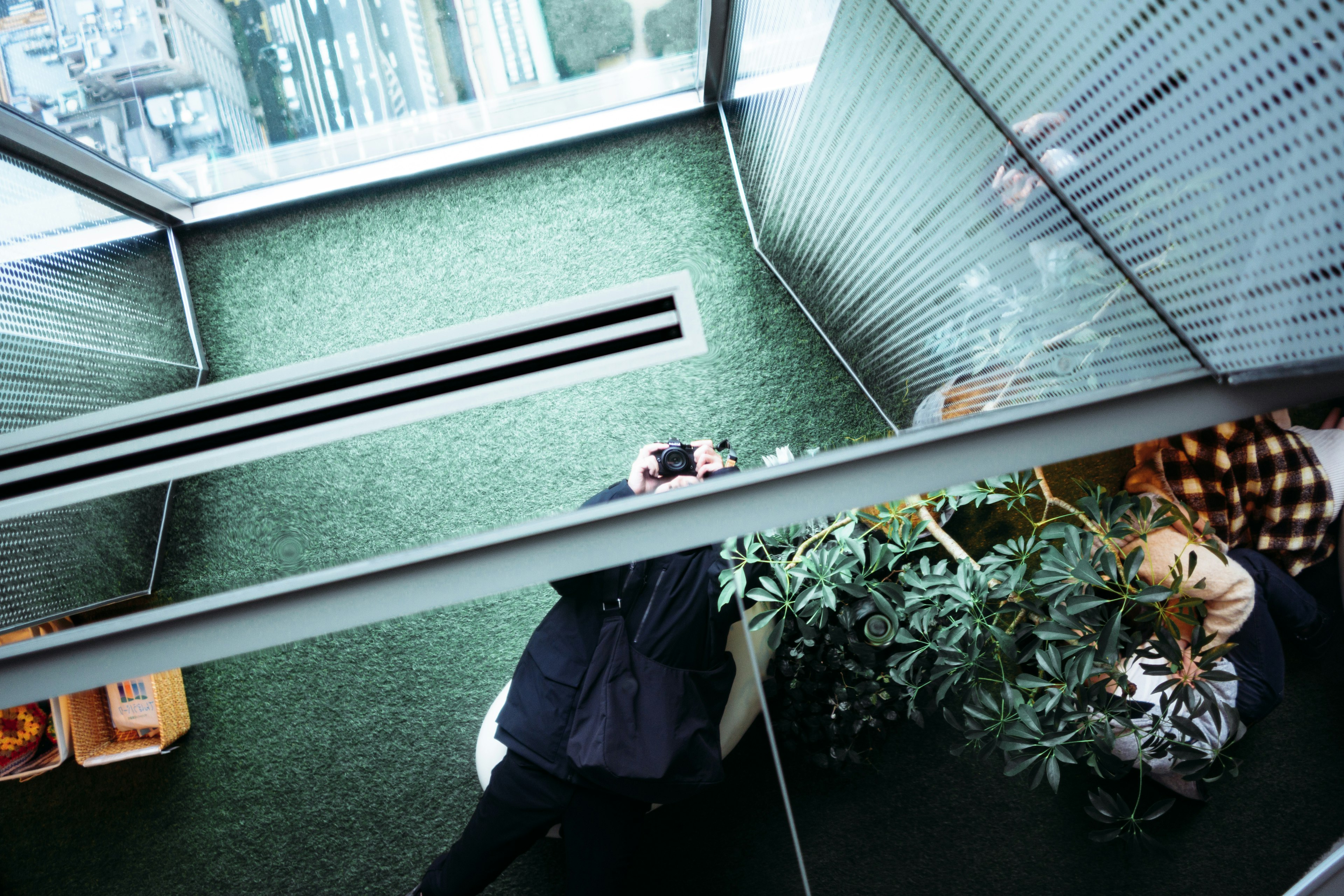 Interior of a high-rise building with green carpet and a person holding a camera