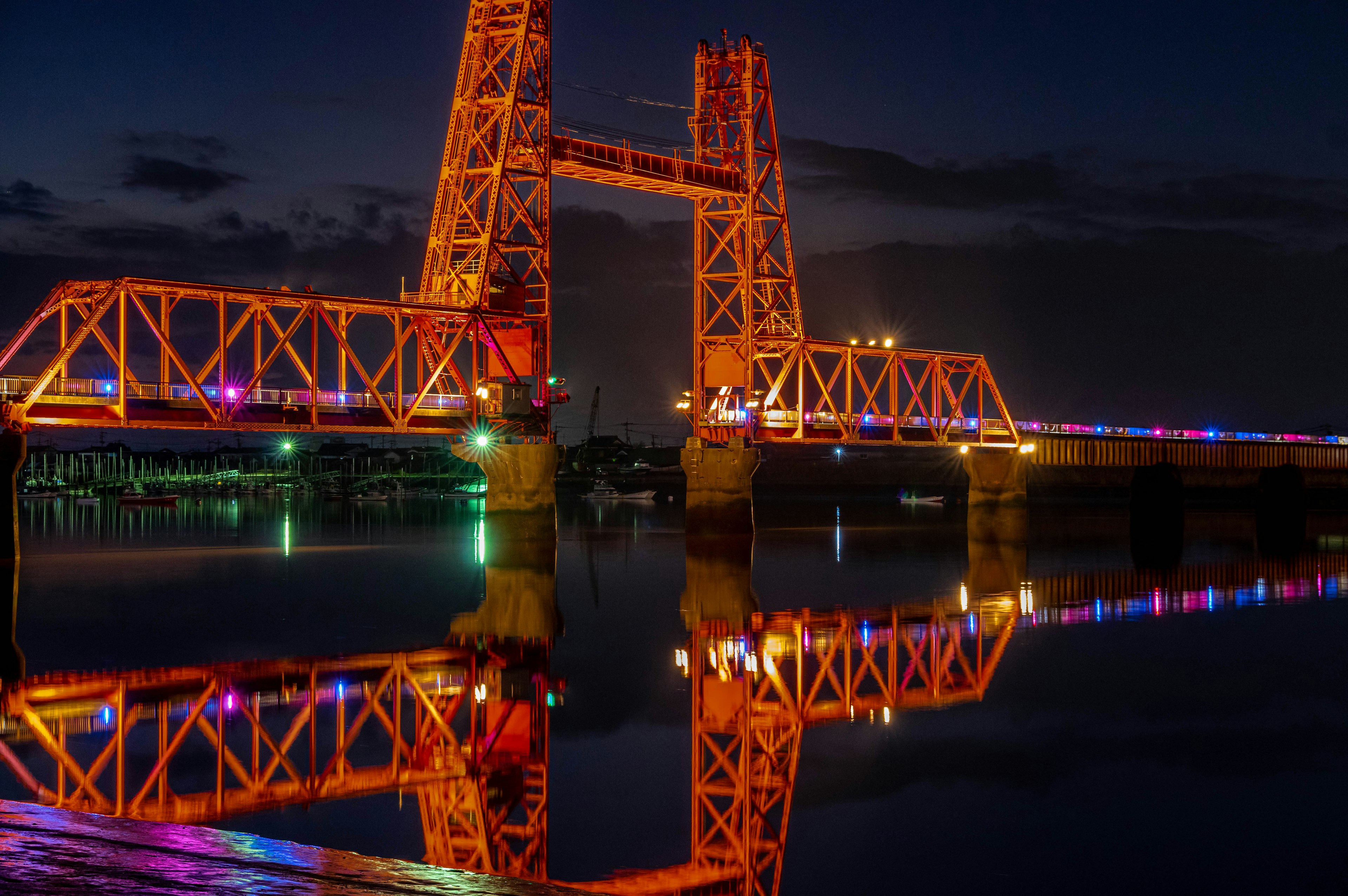 Orange bridge illuminated at night reflecting in water