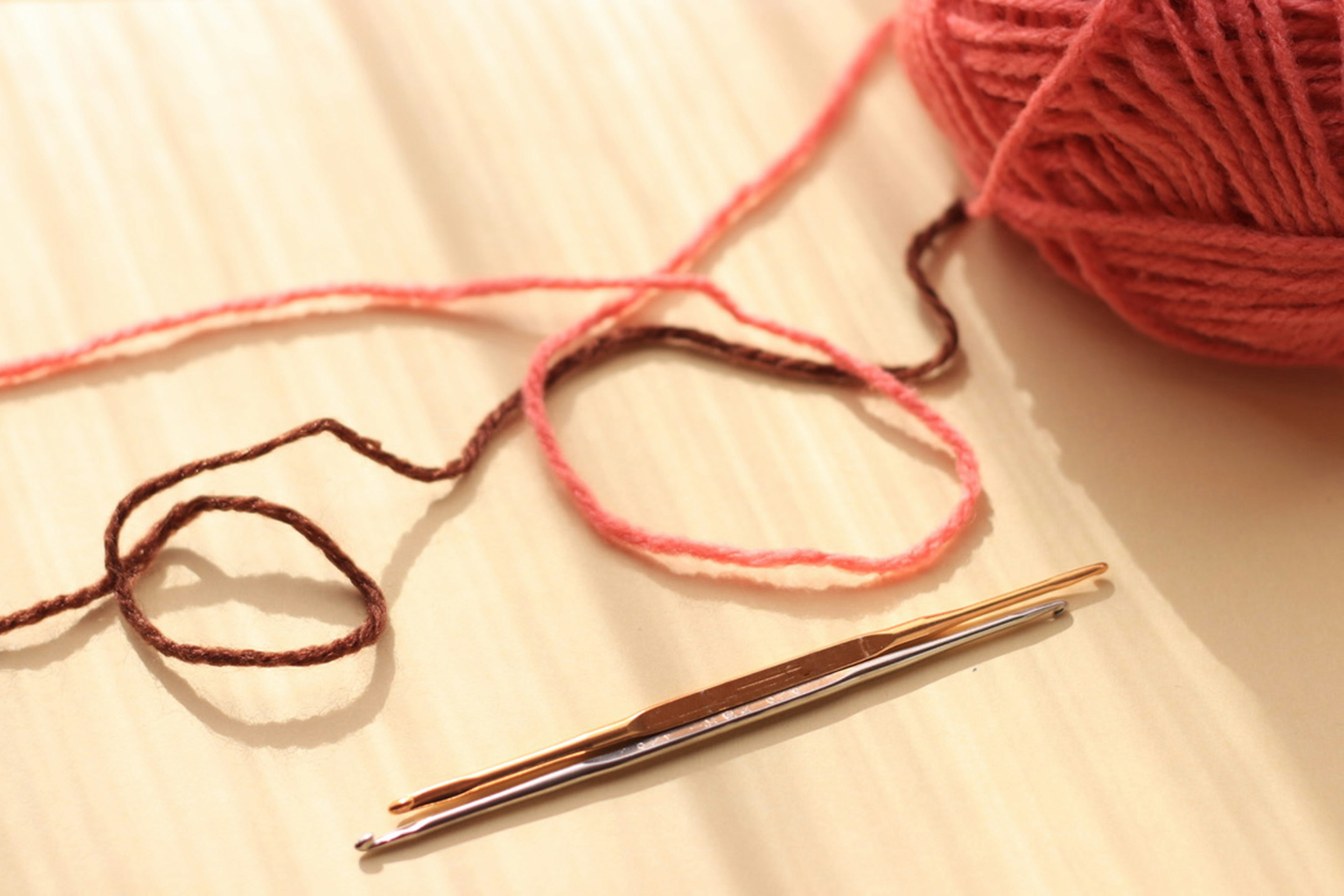 Image of pink yarn and a crochet hook The yarn is soft with bright colors The crochet hook is metallic and shiny