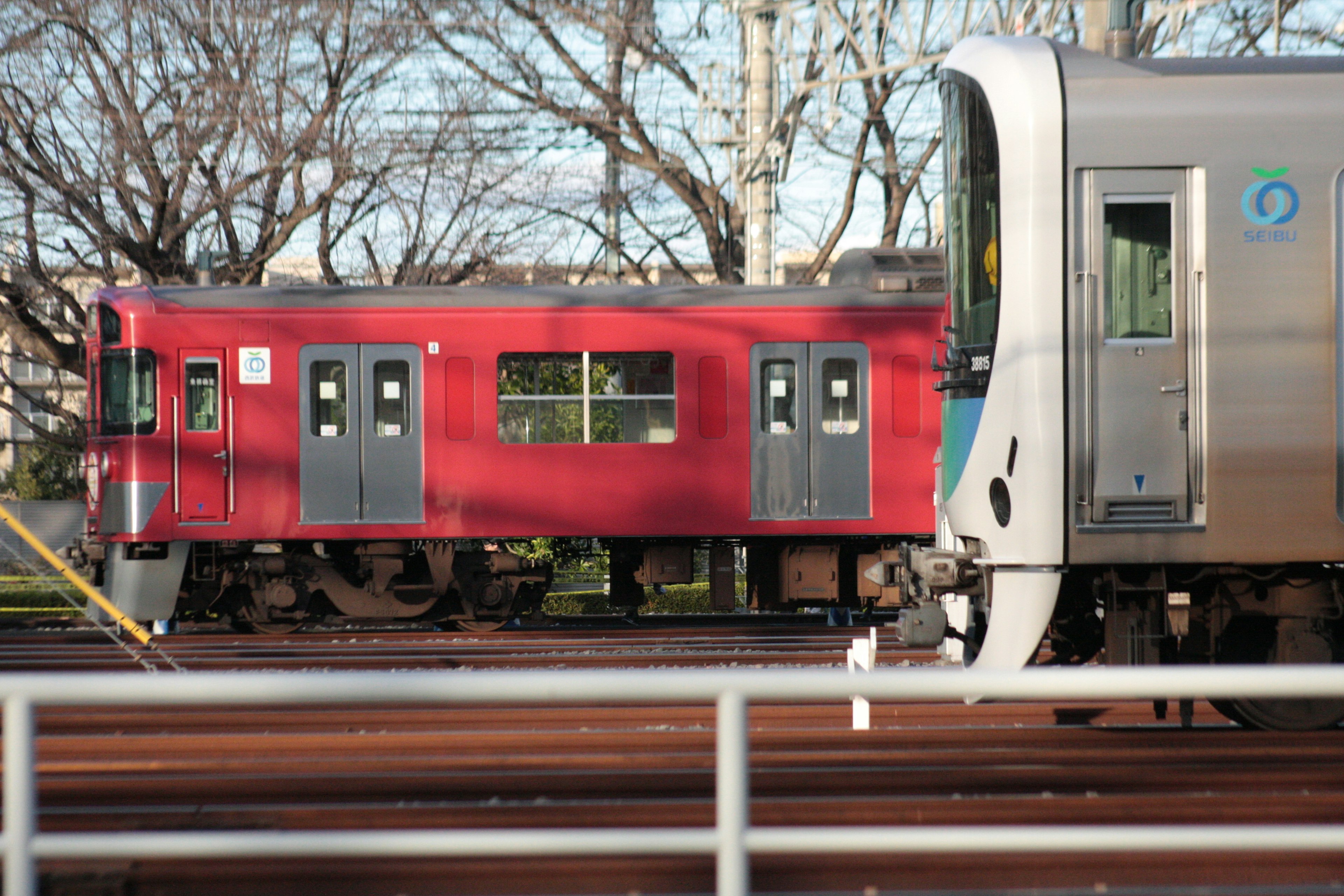 รถไฟสีแดงและรถไฟสีเงินอยู่ข้างกันในบริบทของรถไฟ