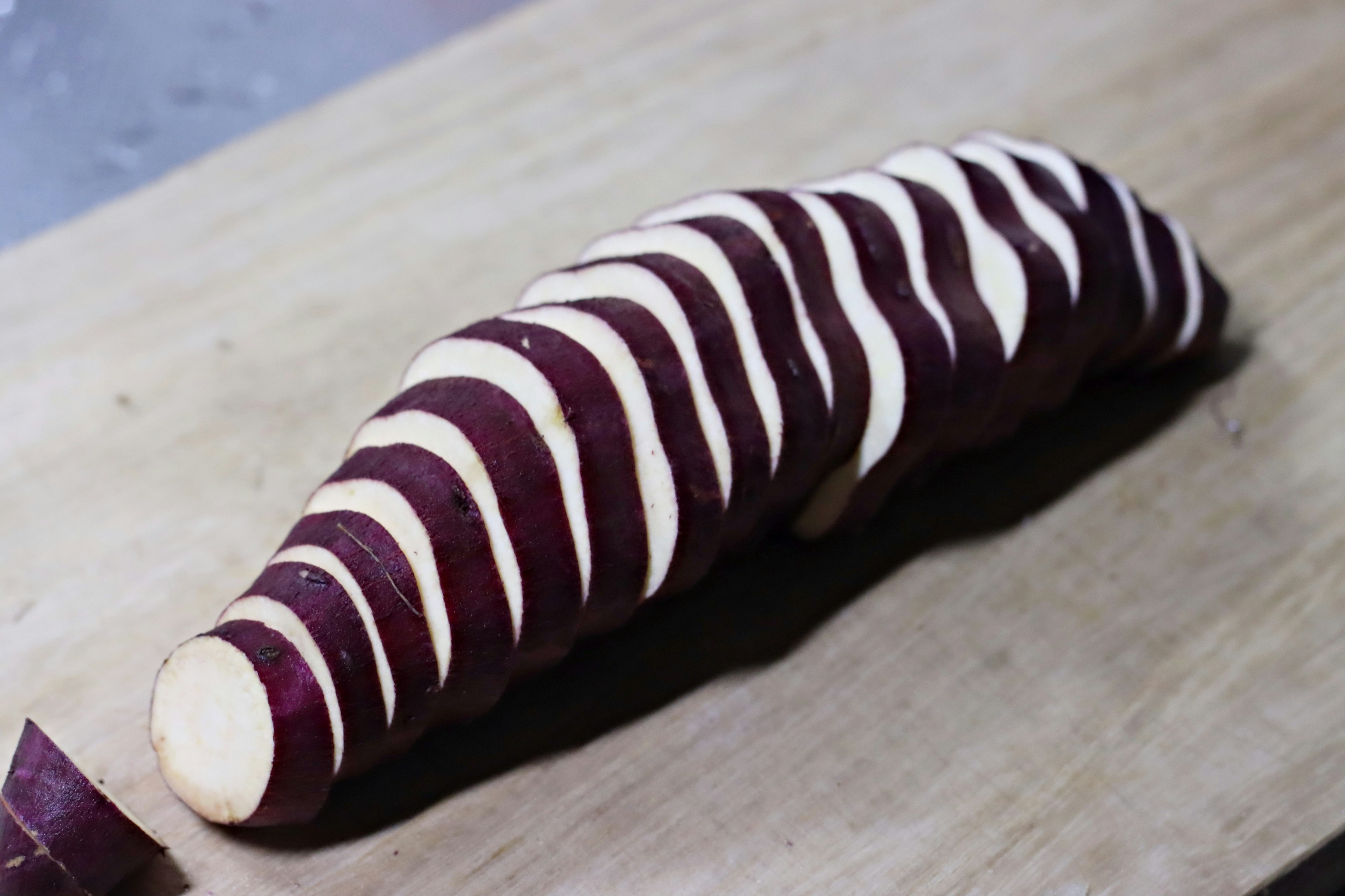 Sliced purple sweet potato arranged on a wooden cutting board