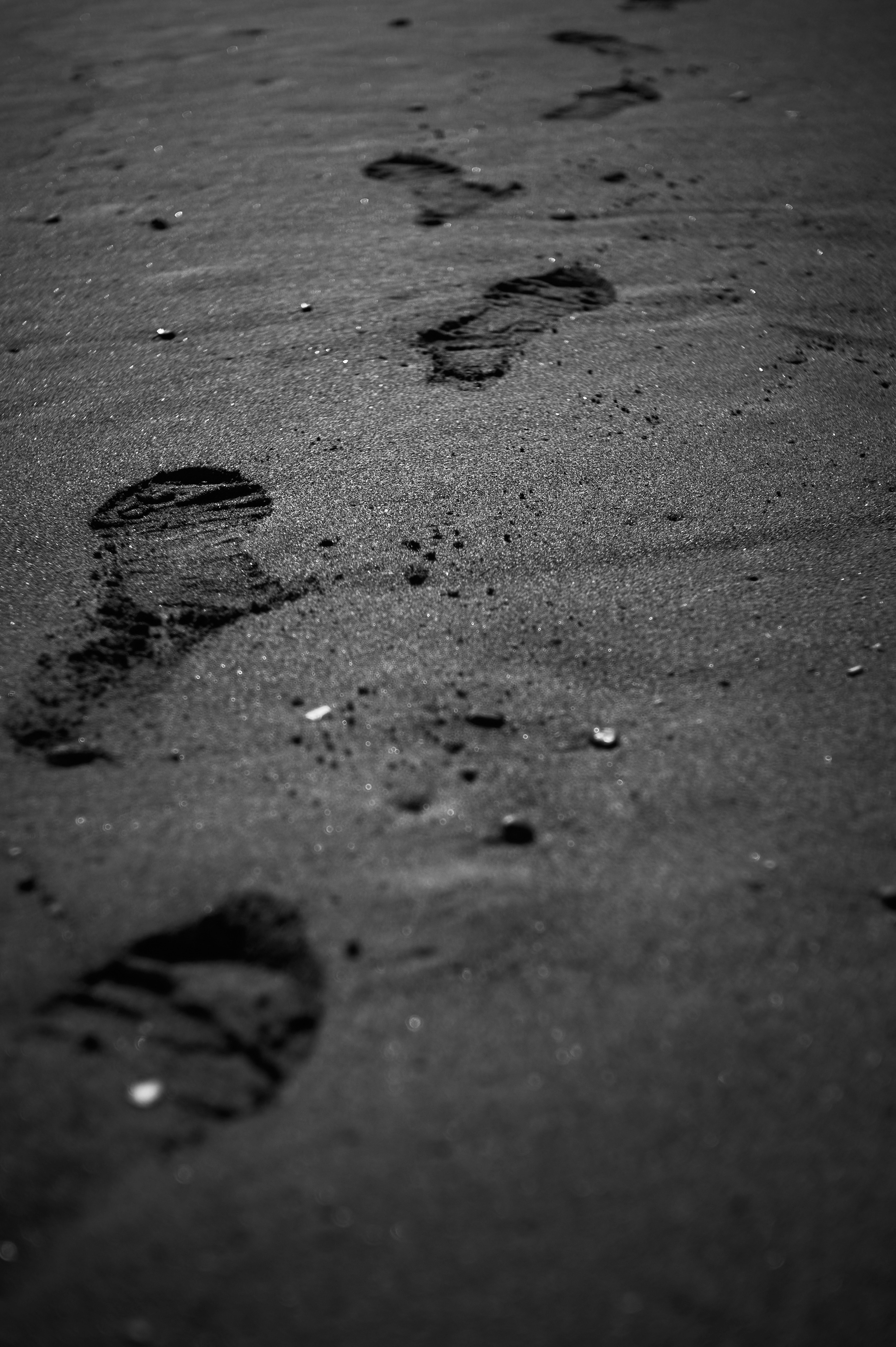 Image en noir et blanc de traces de pas sur une plage de sable