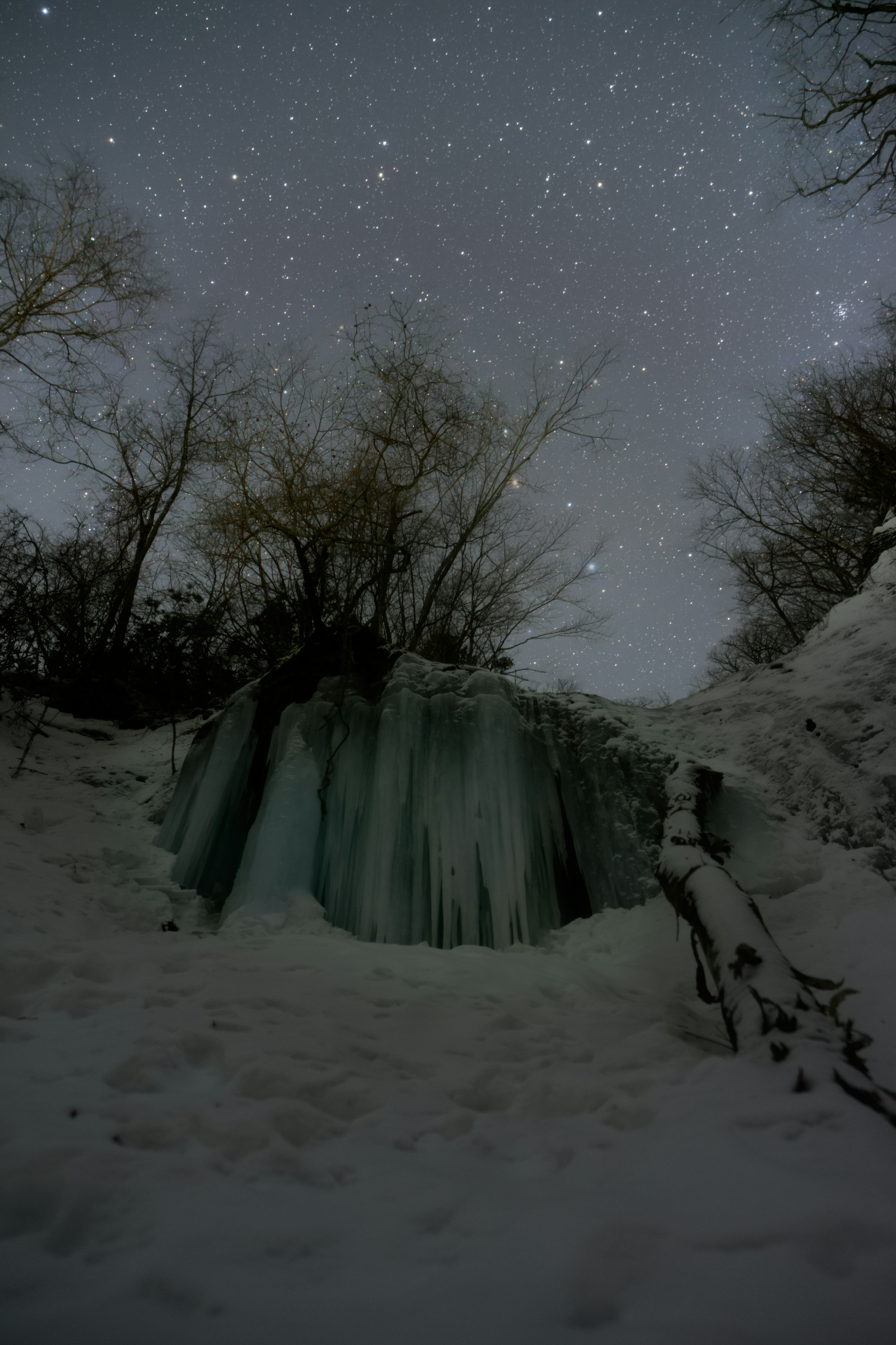 A snowy landscape featuring an ice formation under a starry sky