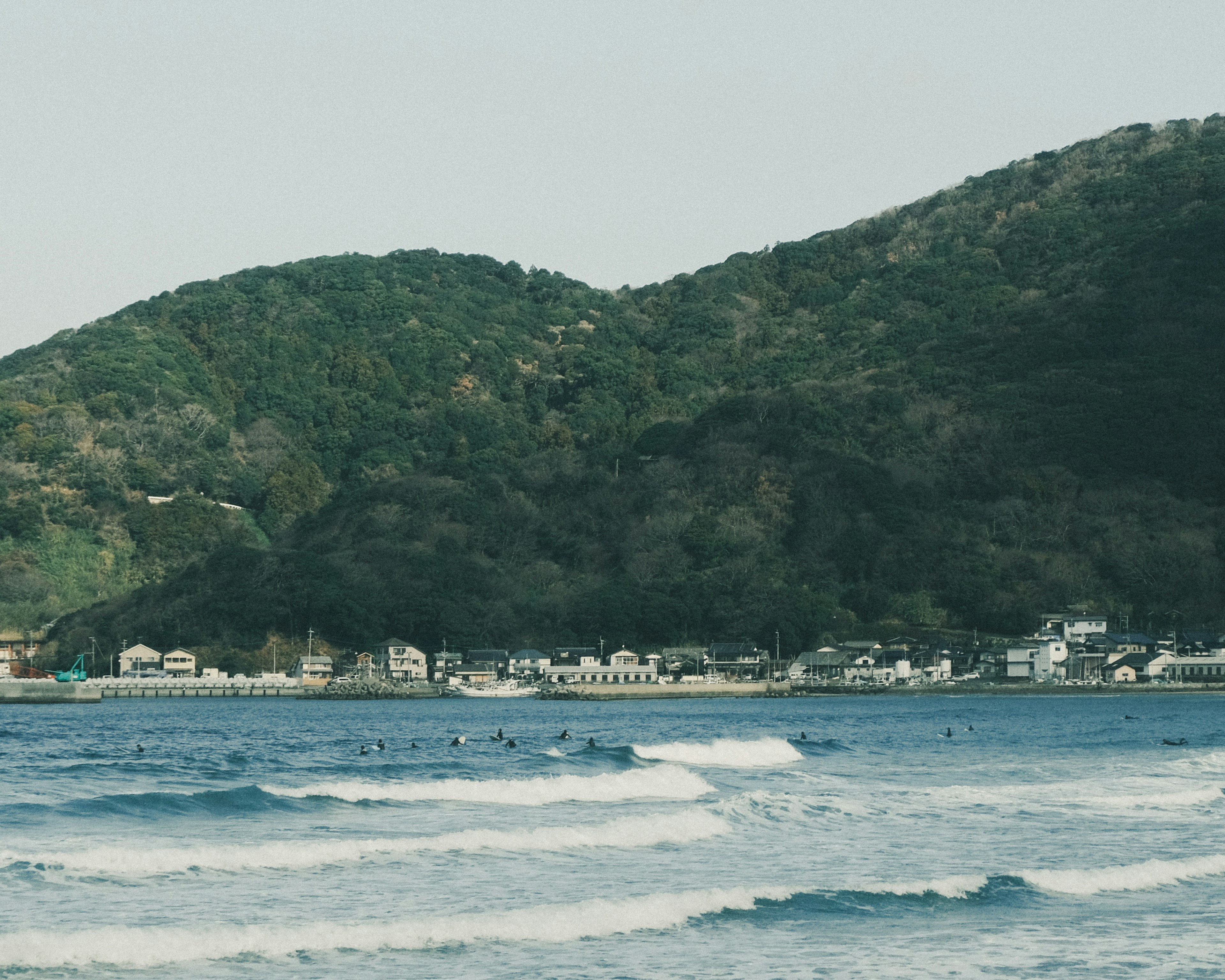 Scenic view of ocean and hills featuring surfers