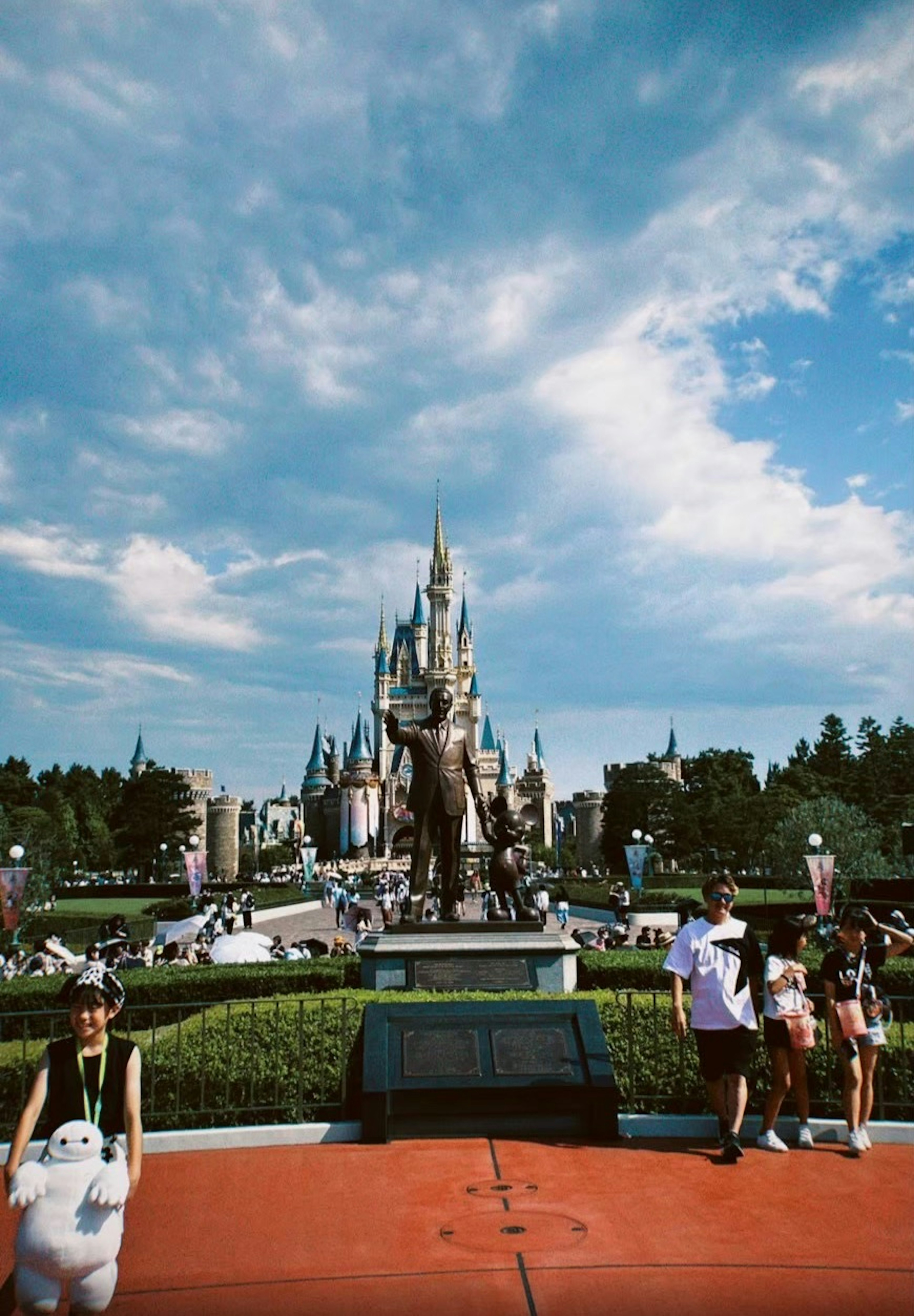 Castillo de Cenicienta en un parque Disney con visitantes y cielo azul