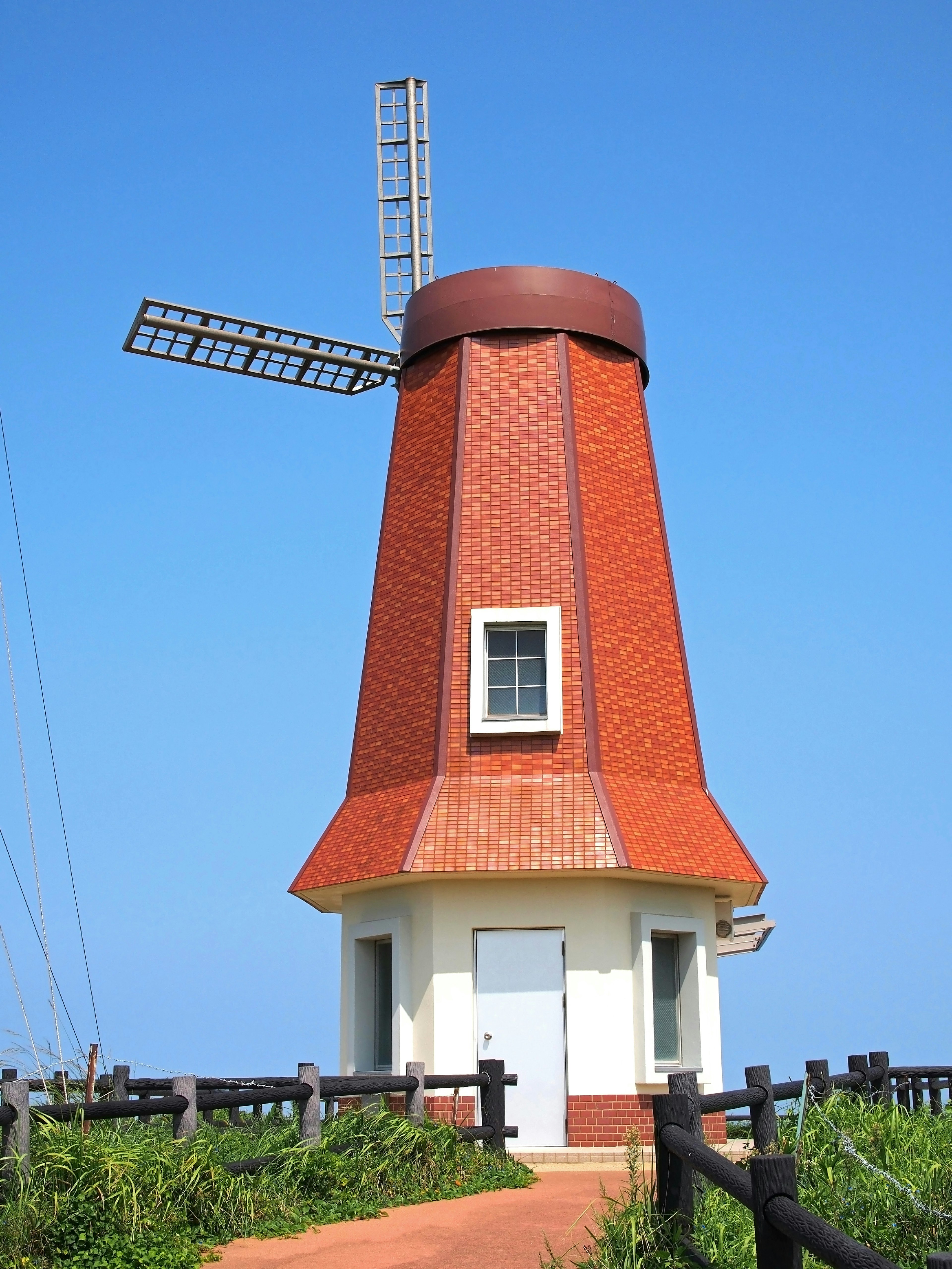 Structure de moulin à vent en briques rouges sous un ciel bleu