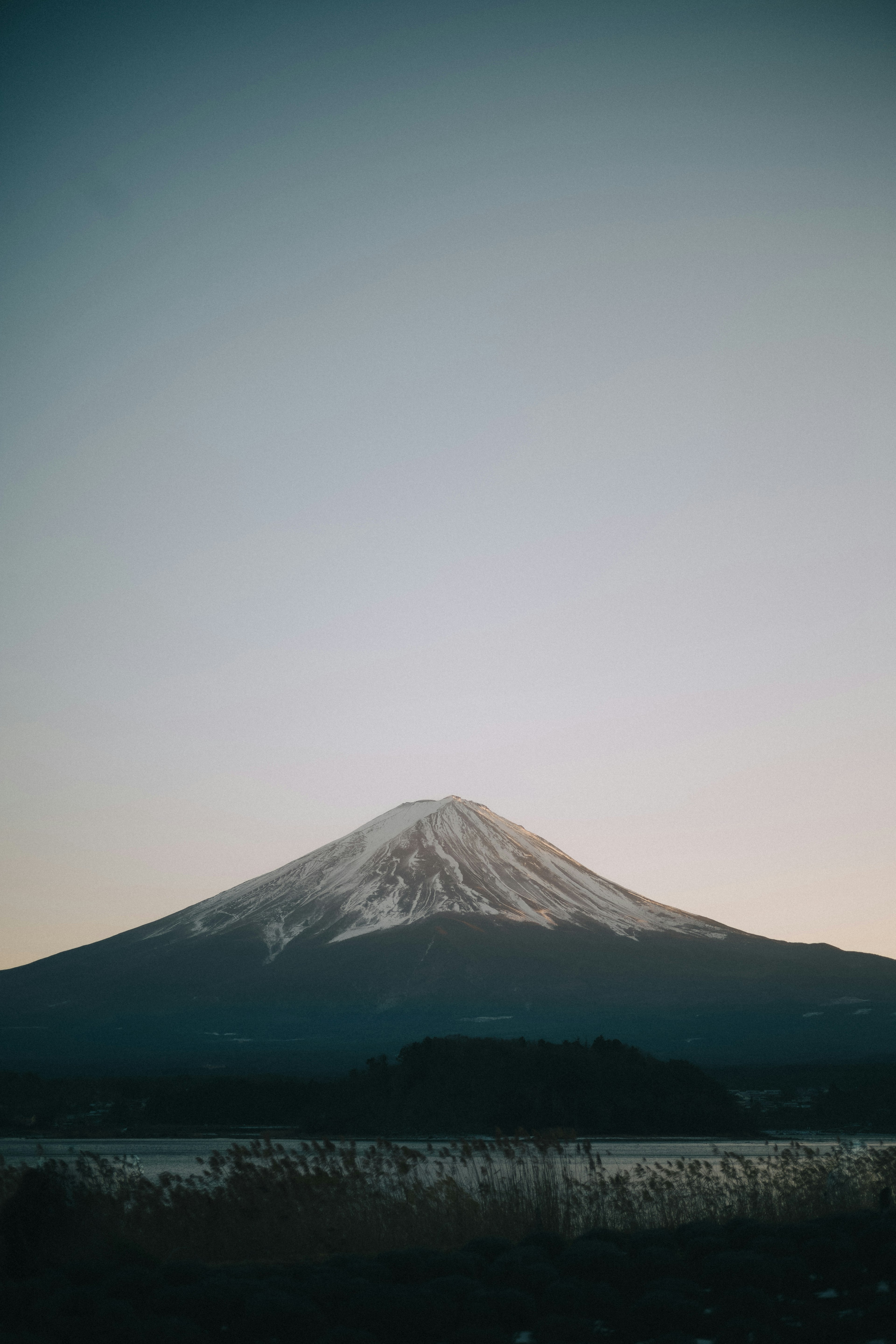 Silhouette of Mount Fuji with a snow-capped peak against a clear sky