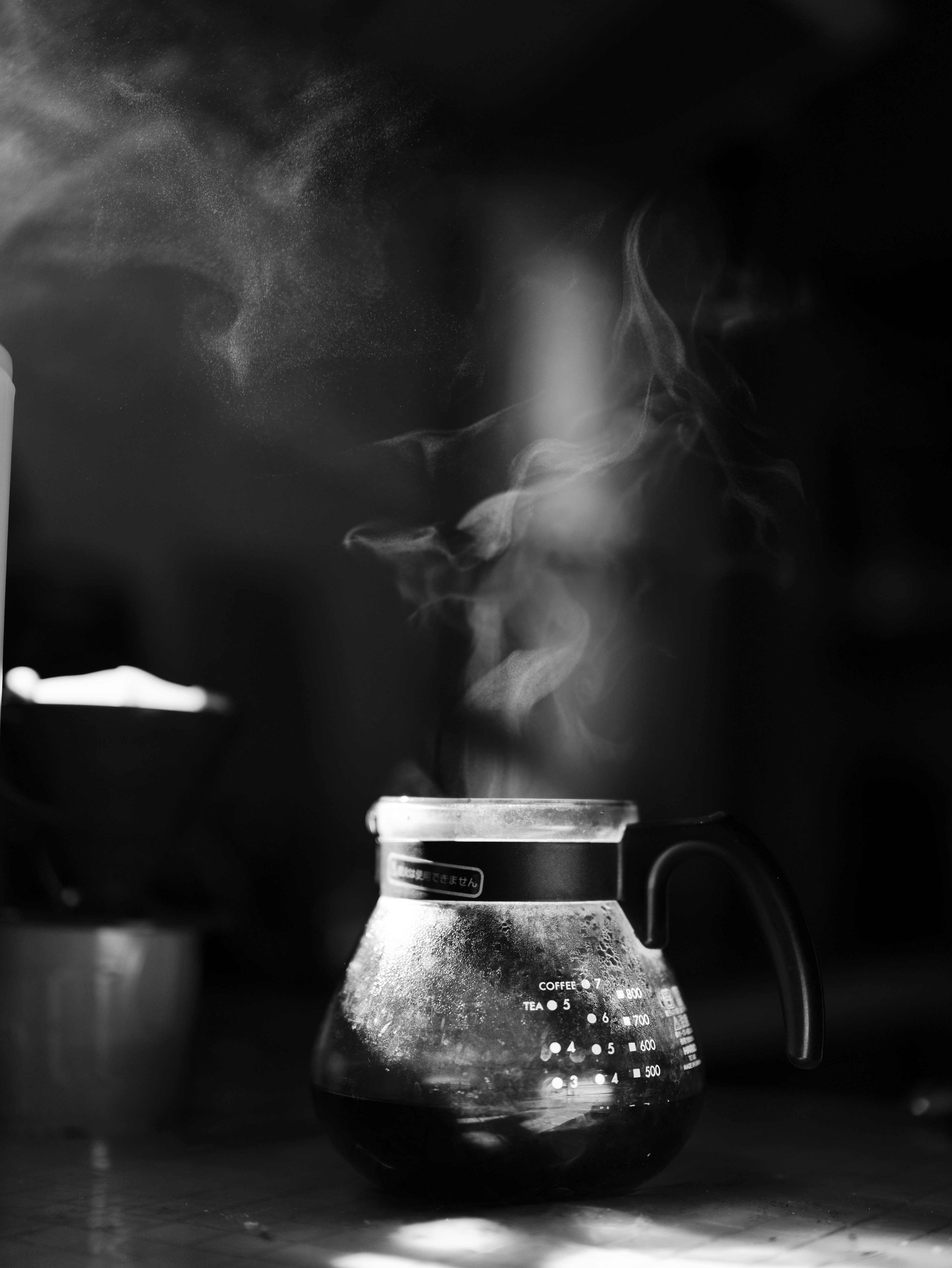 Photo en noir et blanc d'une cafetière avec de la vapeur qui s'élève