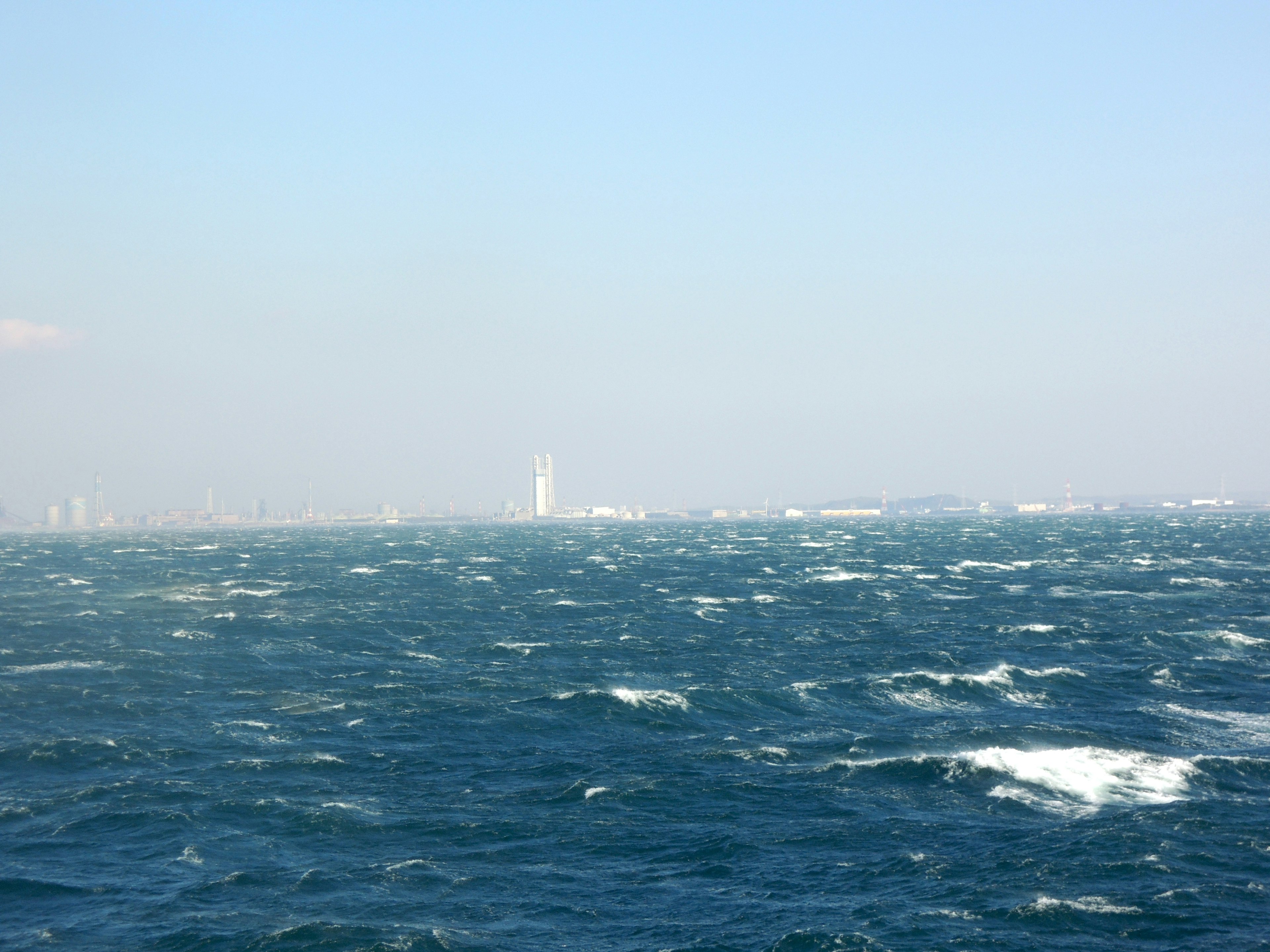 Océan bleu ondulant avec la silhouette lointaine de bâtiments