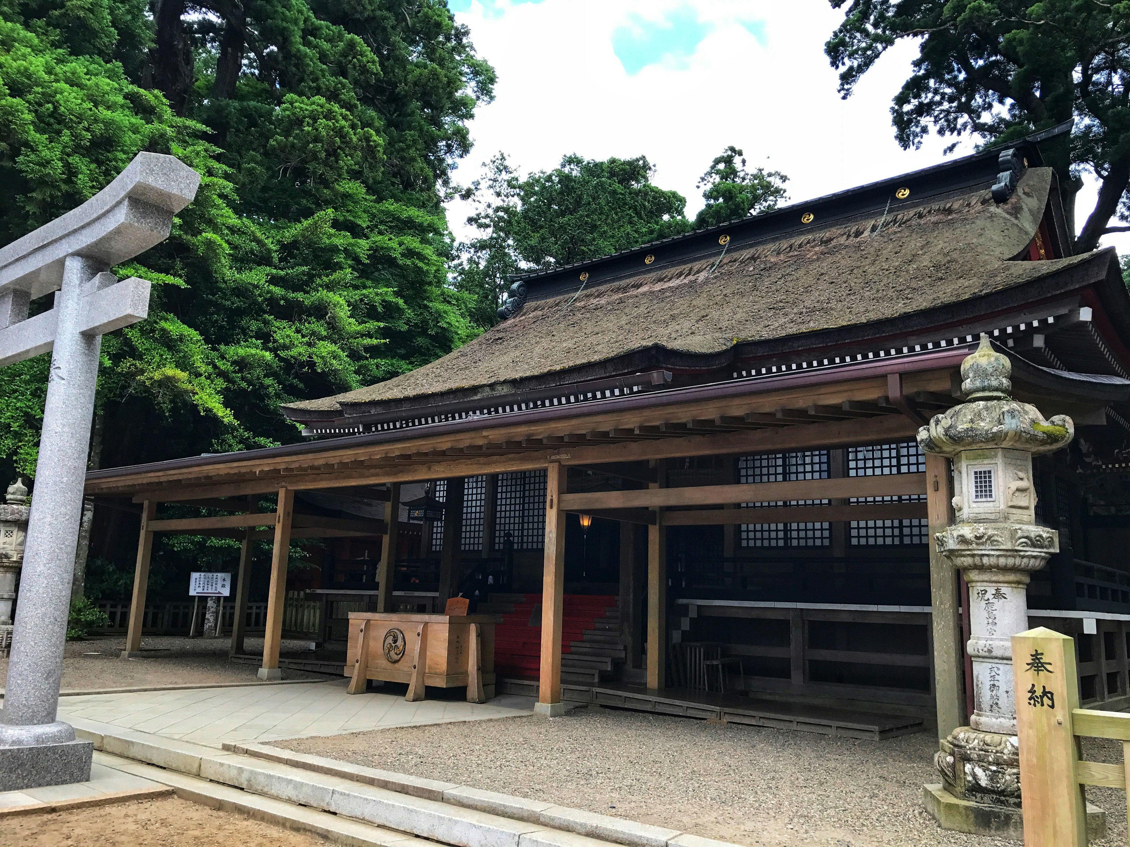 Traditional shrine building with stone lanterns and lush greenery