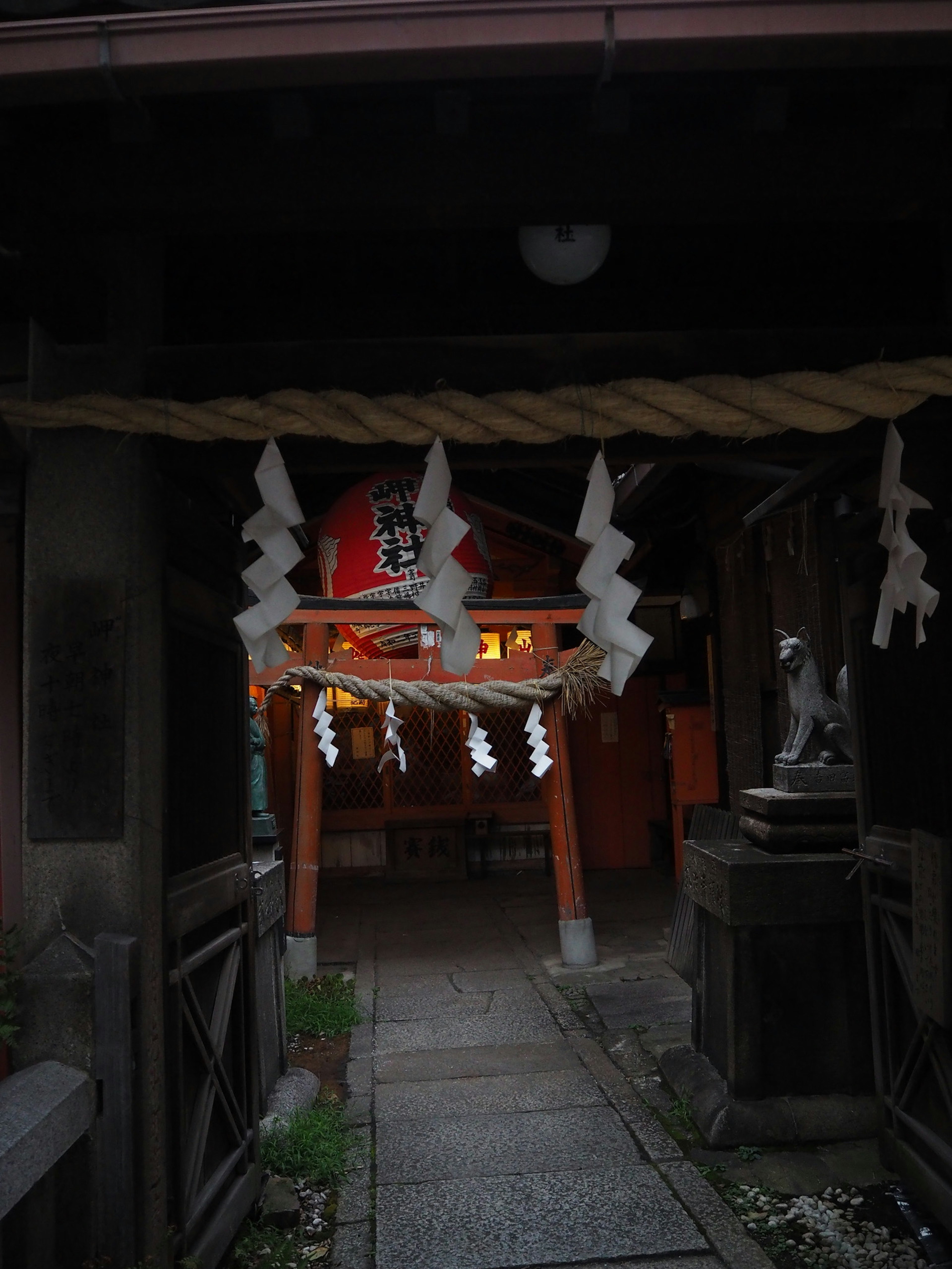 神社の入り口にあるしめ縄と白いお札が飾られた神聖な雰囲気の石畳の道