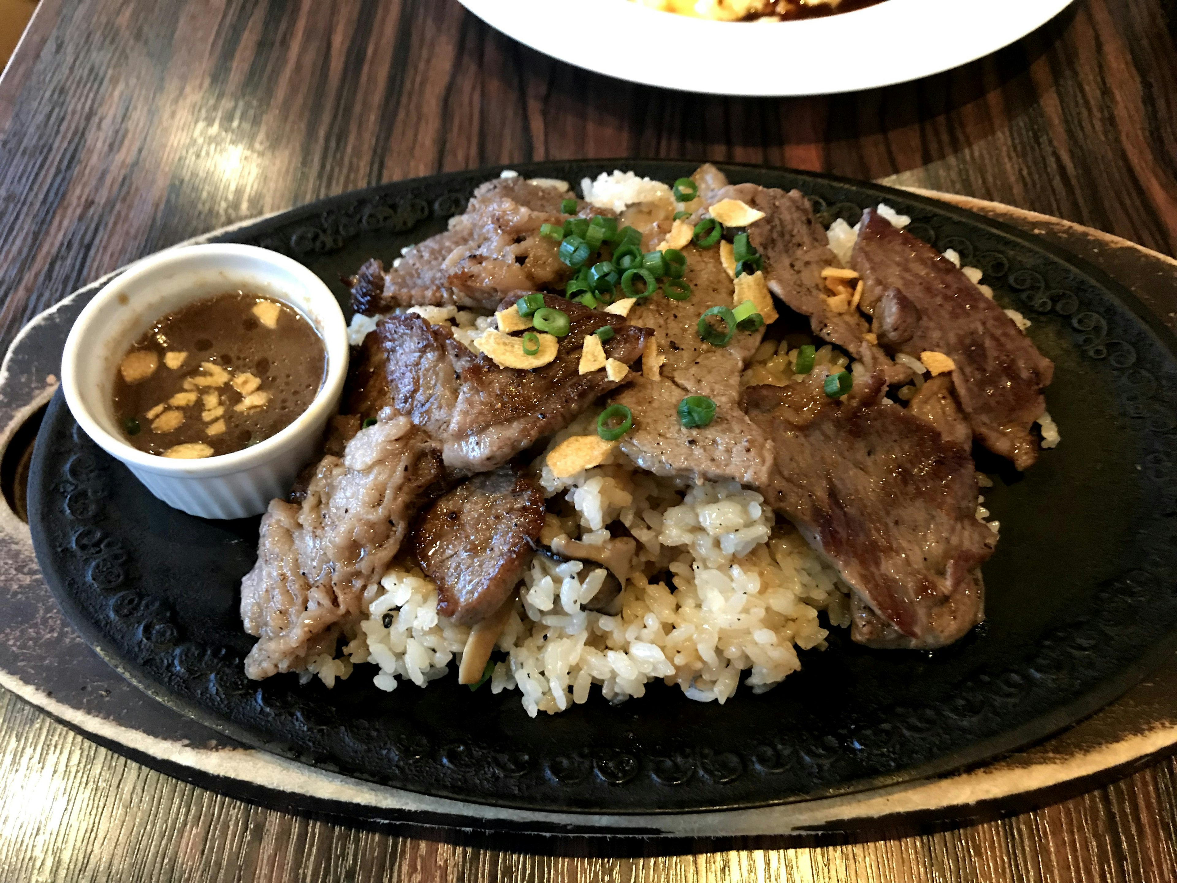 Hidangan daging sapi mendesis disajikan di atas piring panas dengan nasi