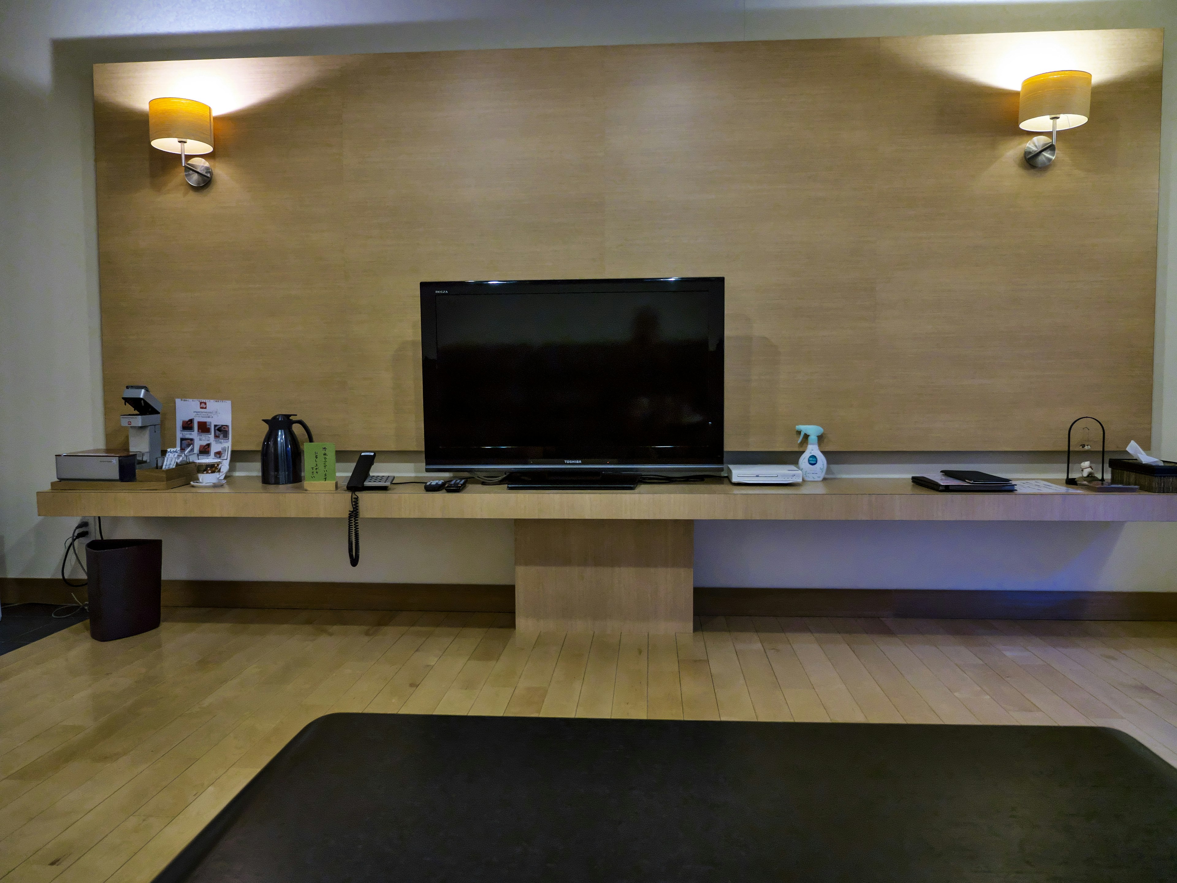 Modern living room setup featuring a wall-mounted television and wooden shelf with lamps on either side