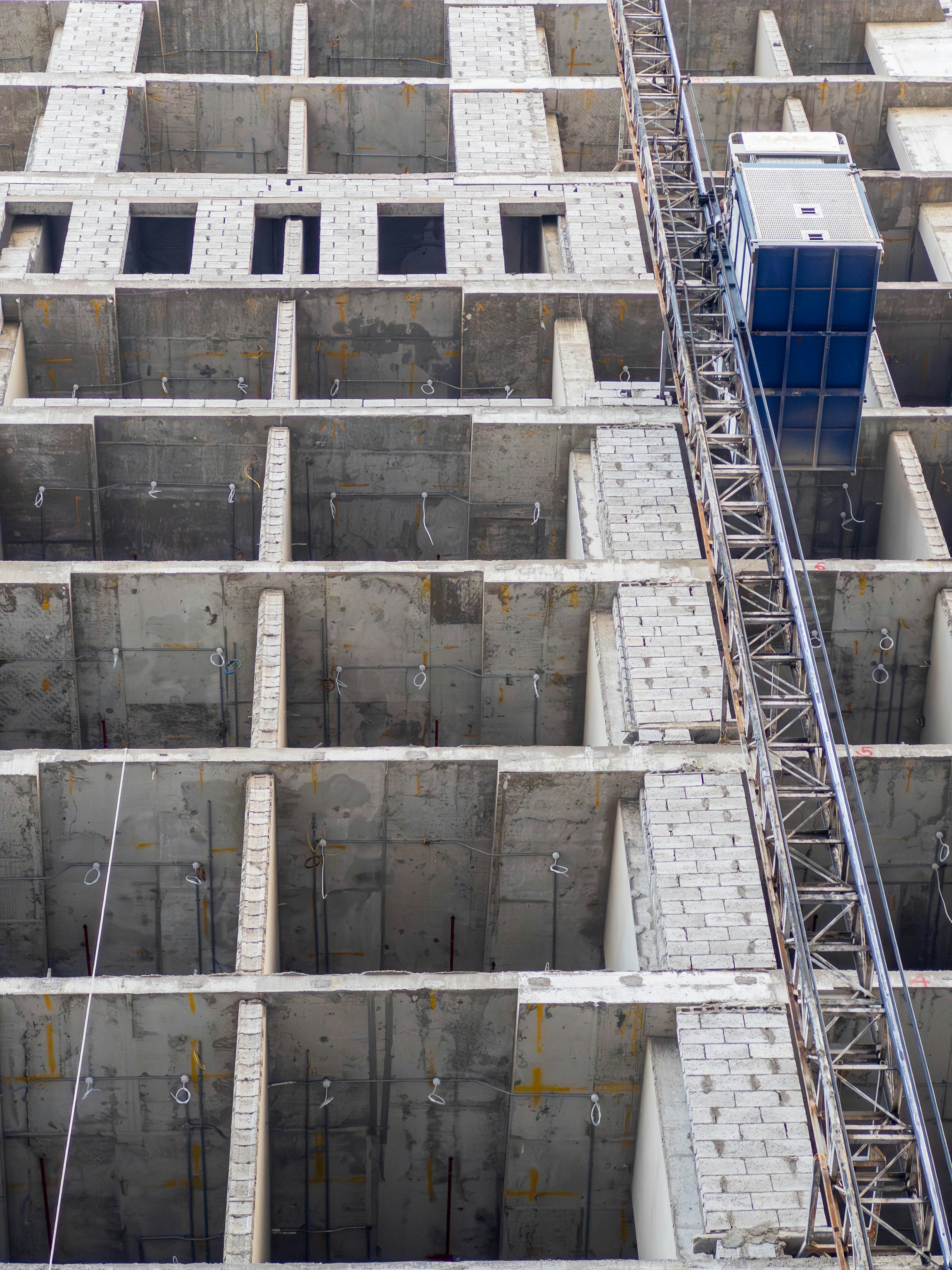 Gros plan d'un chantier de construction de bâtiment en béton avec une grue et des fenêtres vides