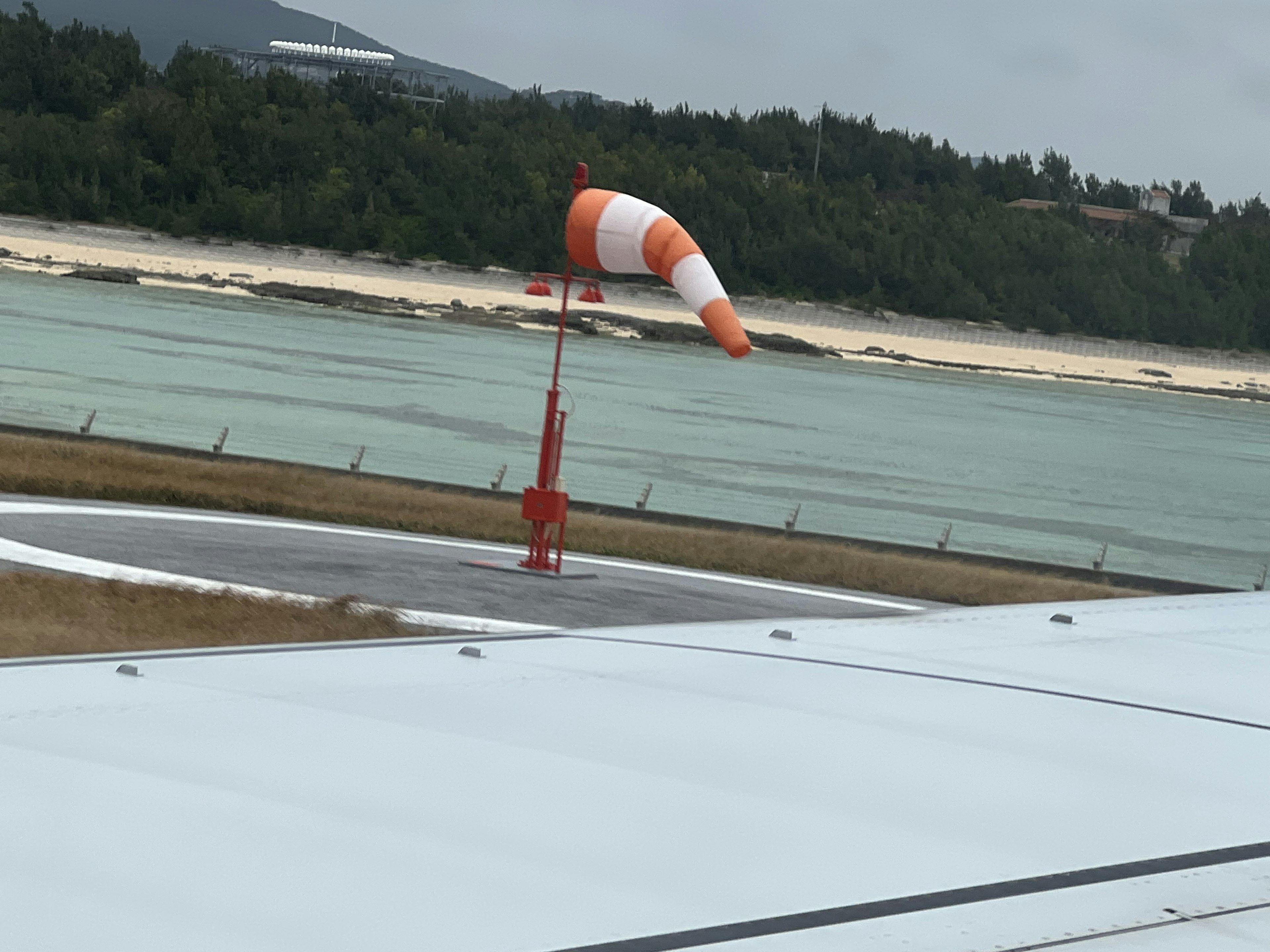 Windsock on the runway at an airport with a coastal view