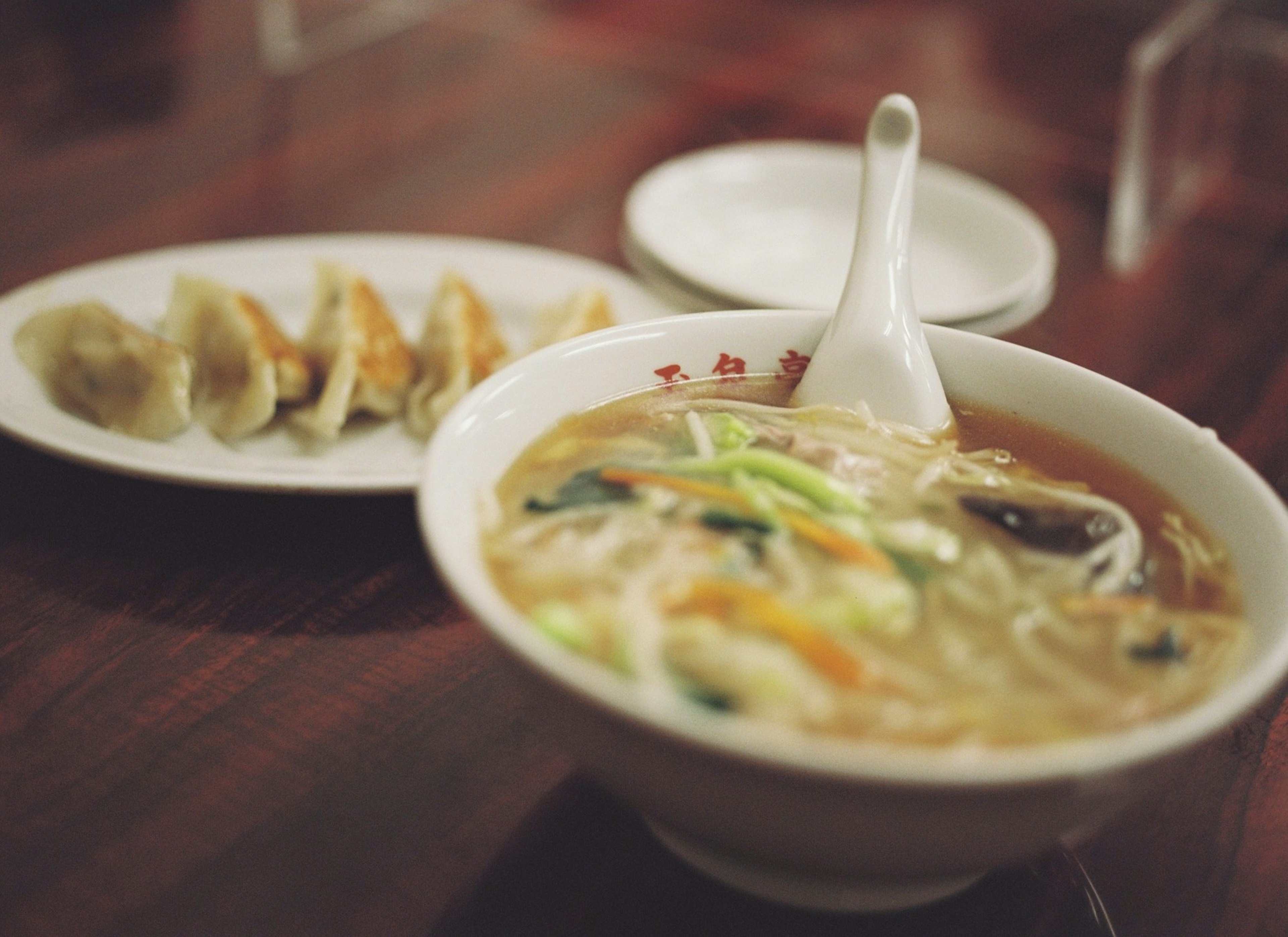 温かいスープと新鮮な野菜を使ったラーメンのボウルと餃子の皿