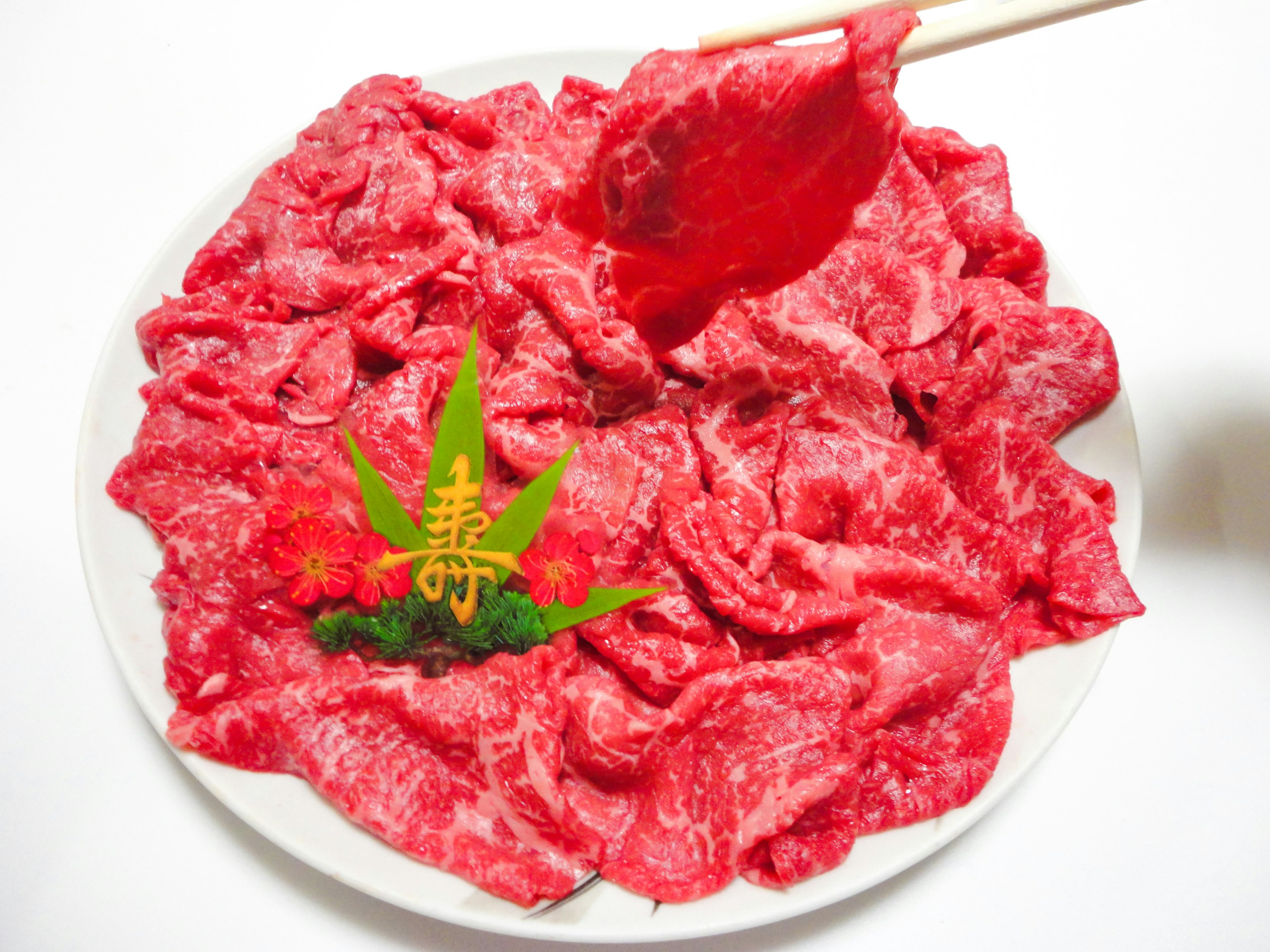 Plate of thinly sliced red meat garnished with green decoration