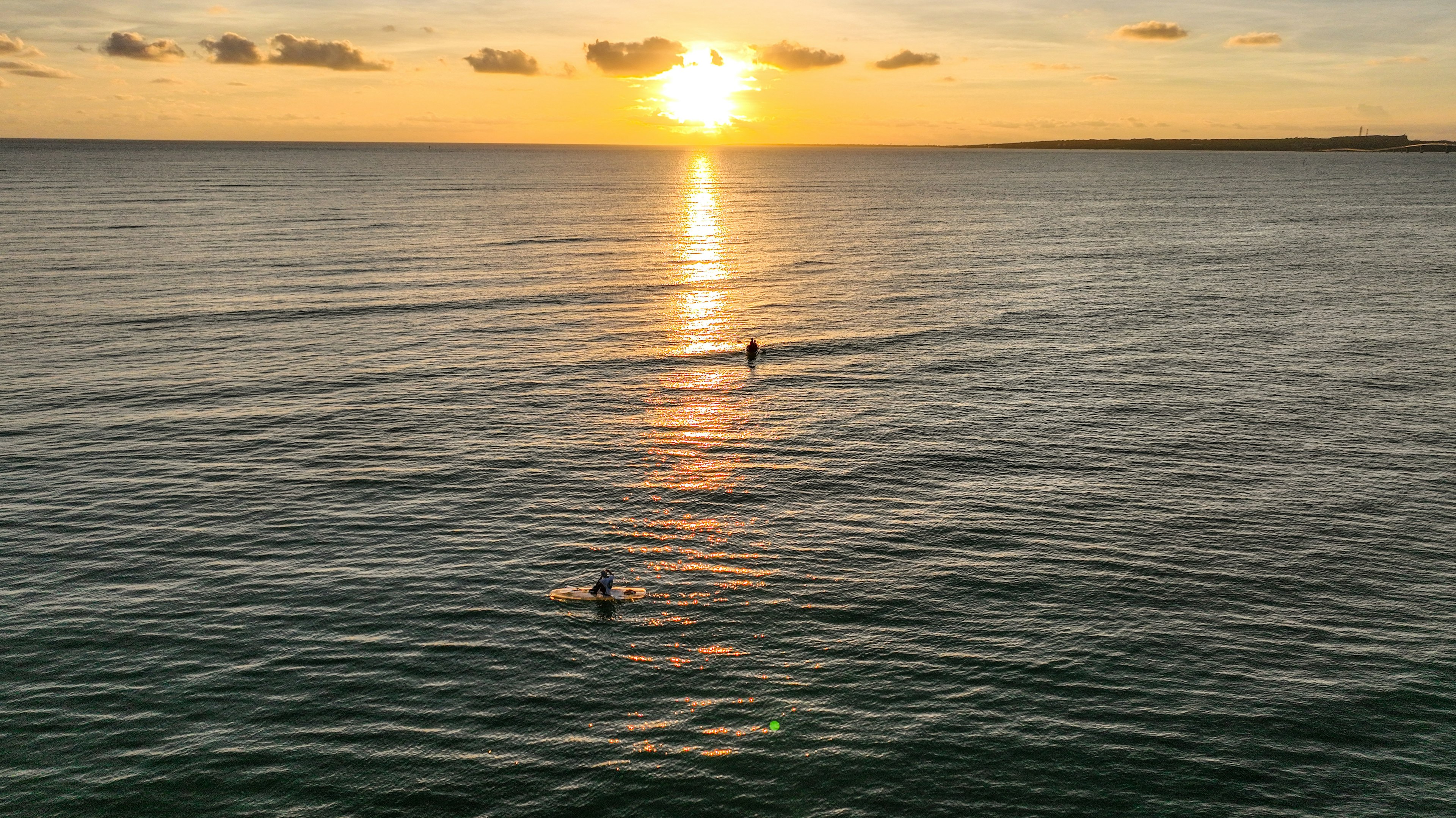 Des personnes surfant dans l'océan au coucher du soleil